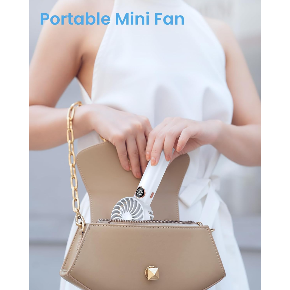 Eine Person legt einen weißen Mini-Ventilator in eine beige Handtasche. Der Ventilator hat ein Display.