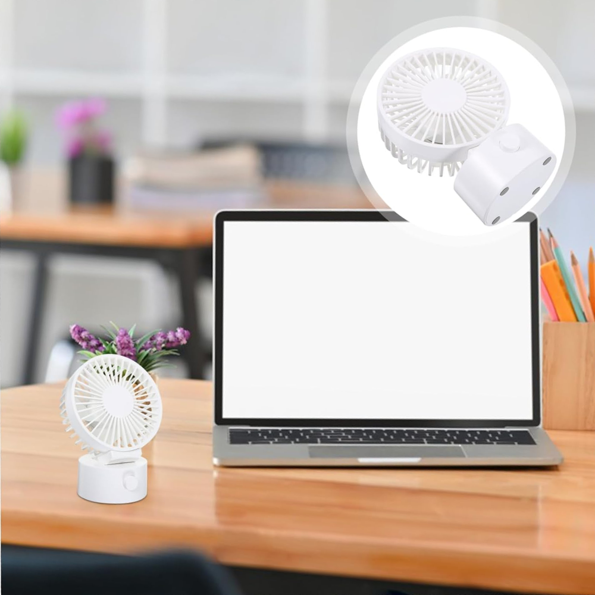 Ein weißer Ventilator neben einem Laptop auf einem Holztisch.