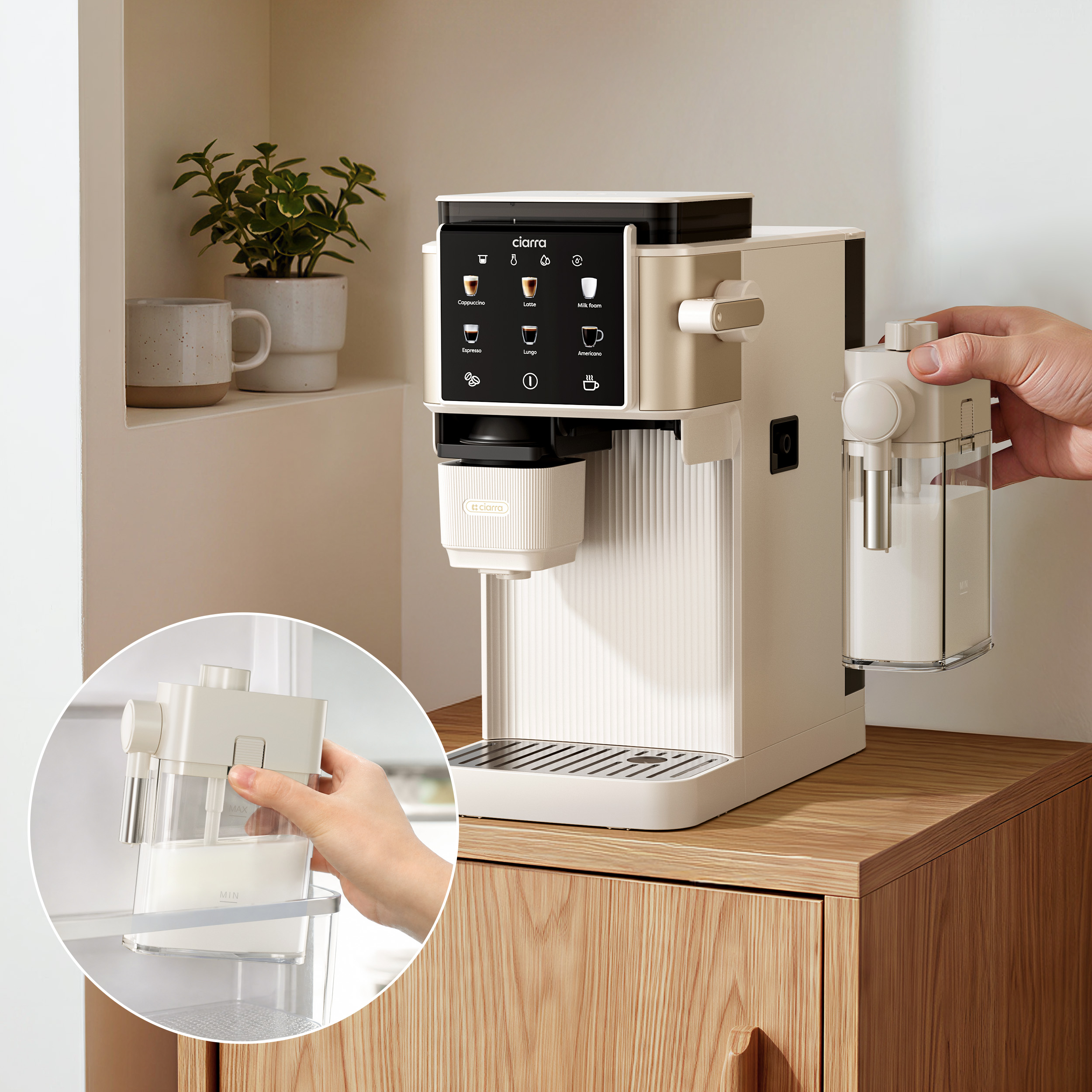 Una cafetera beige con un recipiente de leche sostenido por una mano.
