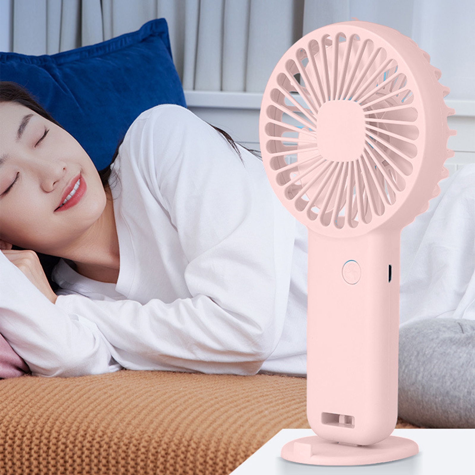 Eine Frau schläft neben einem rosafarbenen Handventilator.