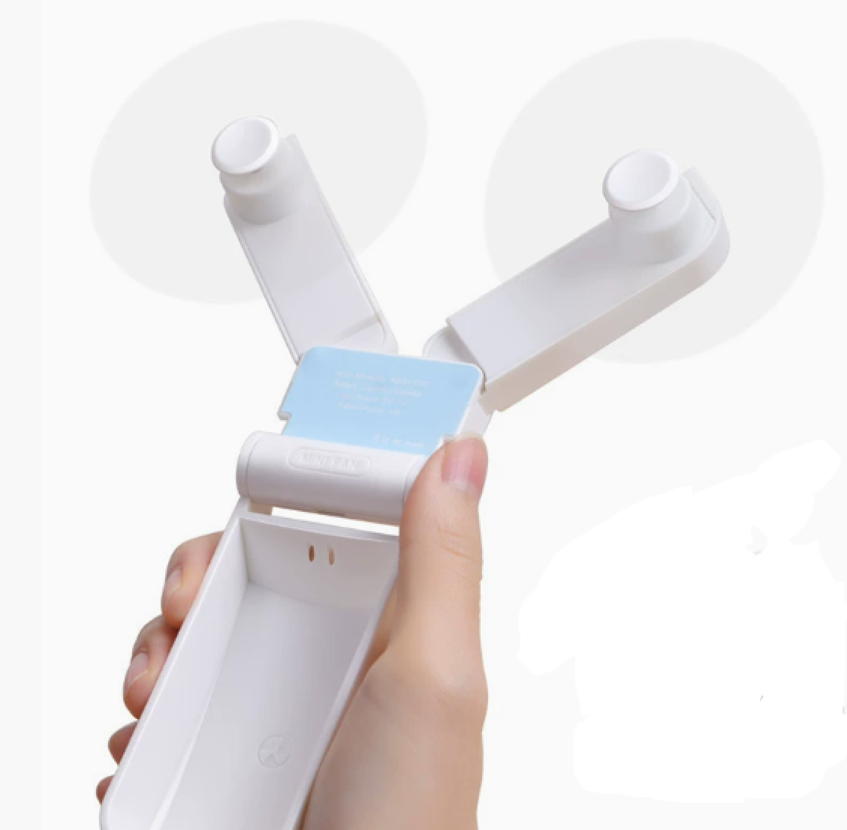 Eine Hand hält einen weißen, faltbaren Mini-Ventilator mit zwei Propellern.