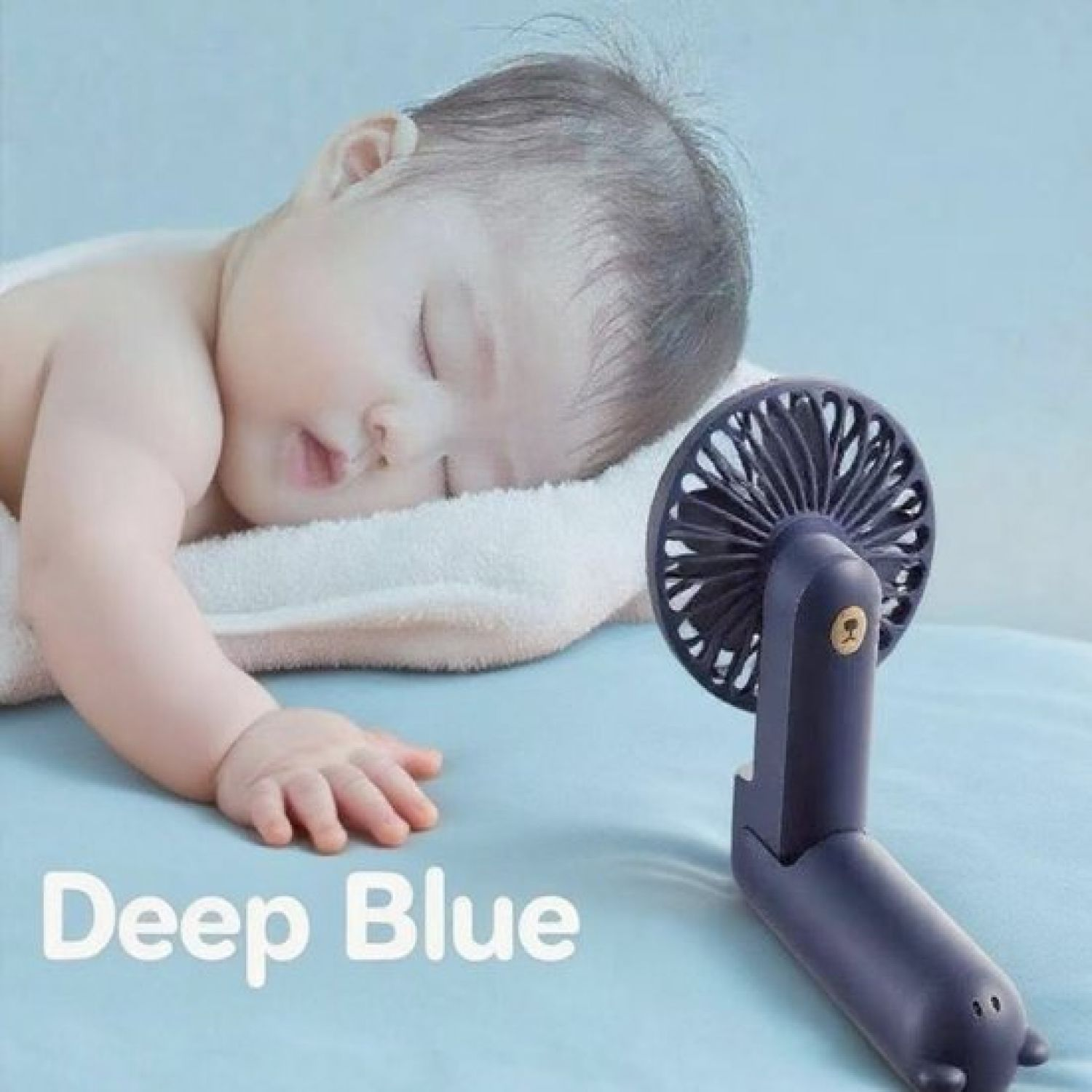 Ein schlafendes Baby liegt neben einem dunklen, faltbaren Lüfter mit Bärenmotiv.