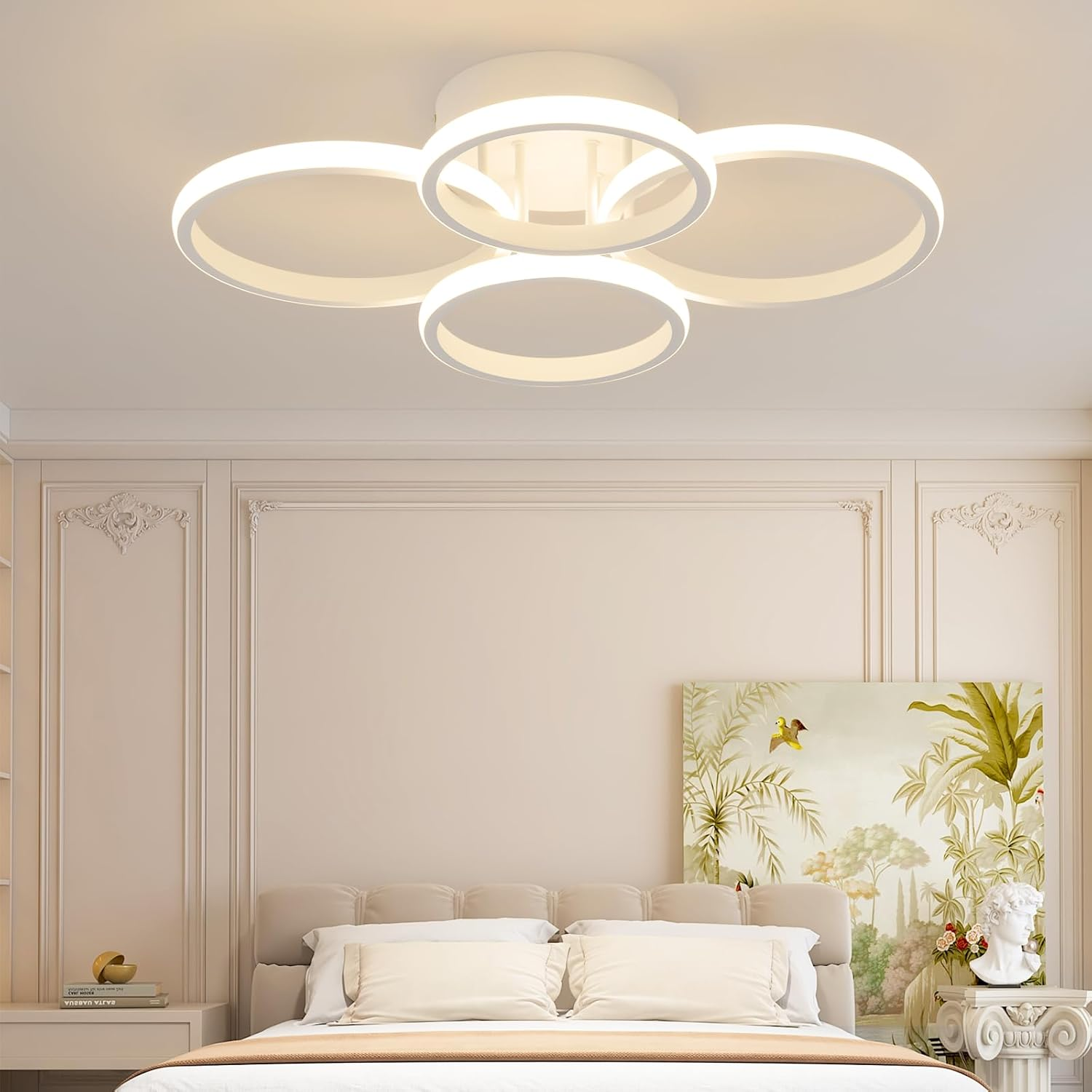 Lámpara de techo blanca moderna con cuatro anillos entrelazados sobre una cama.
