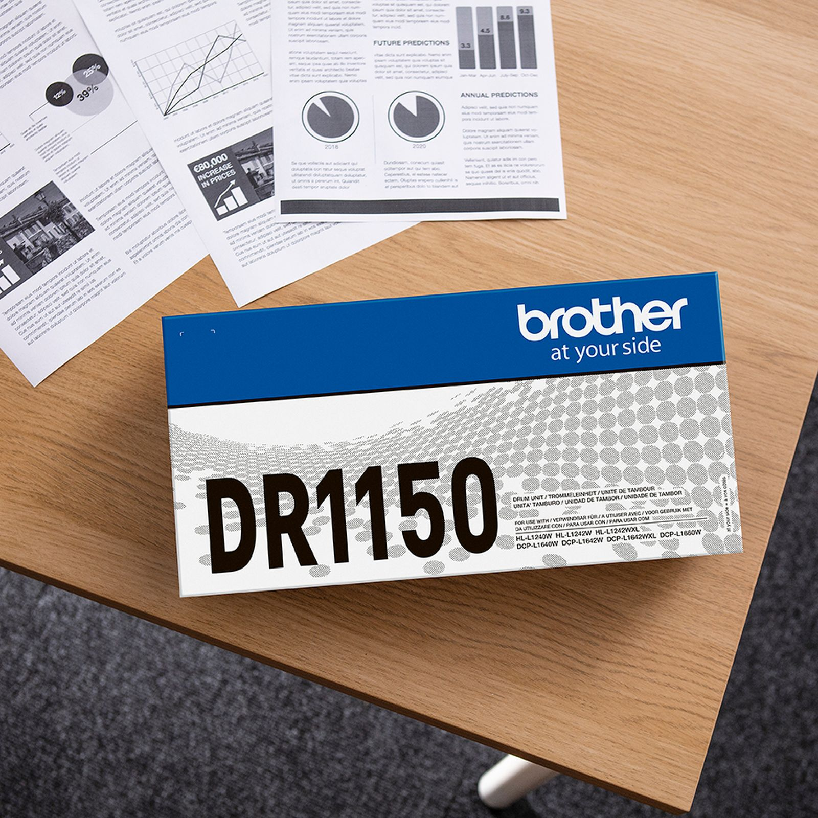 Unità tamburo Brother DR1150 su tavolo in legno con documenti.
