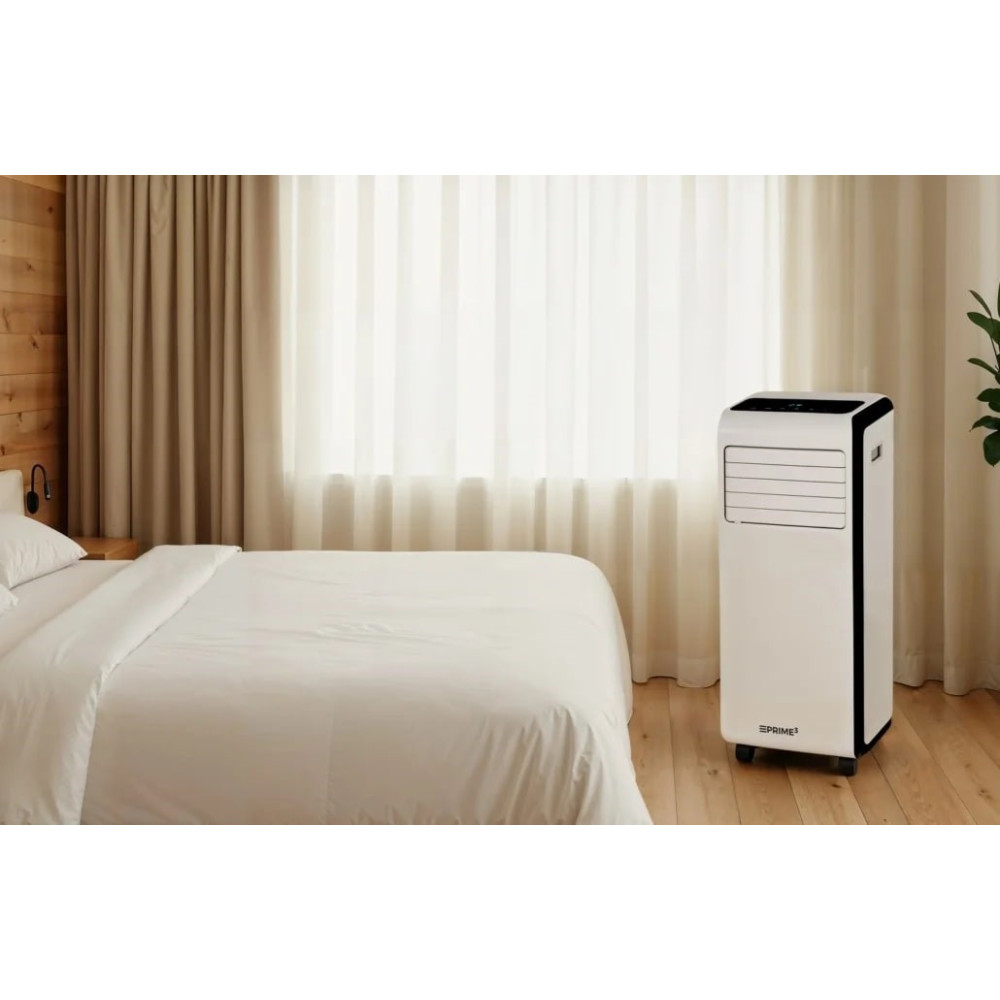Un condizionatore d'aria portatile bianco accanto a un letto con lenzuola bianche.