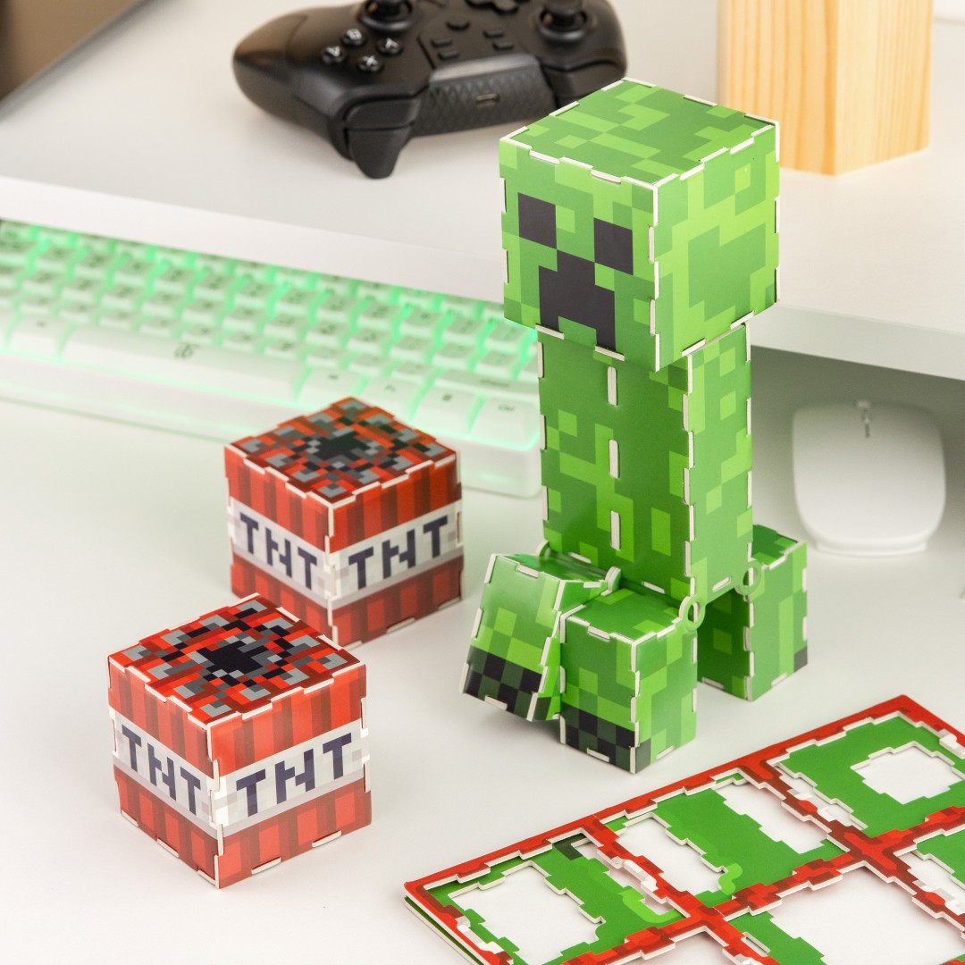 Minecraft Creeper Figur, TNT-Blöcke, Tastatur, Maus und Controller auf einem Schreibtisch.