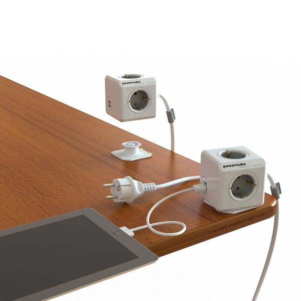 Prese bianche a cubo su scrivania in legno con tablet e spina.