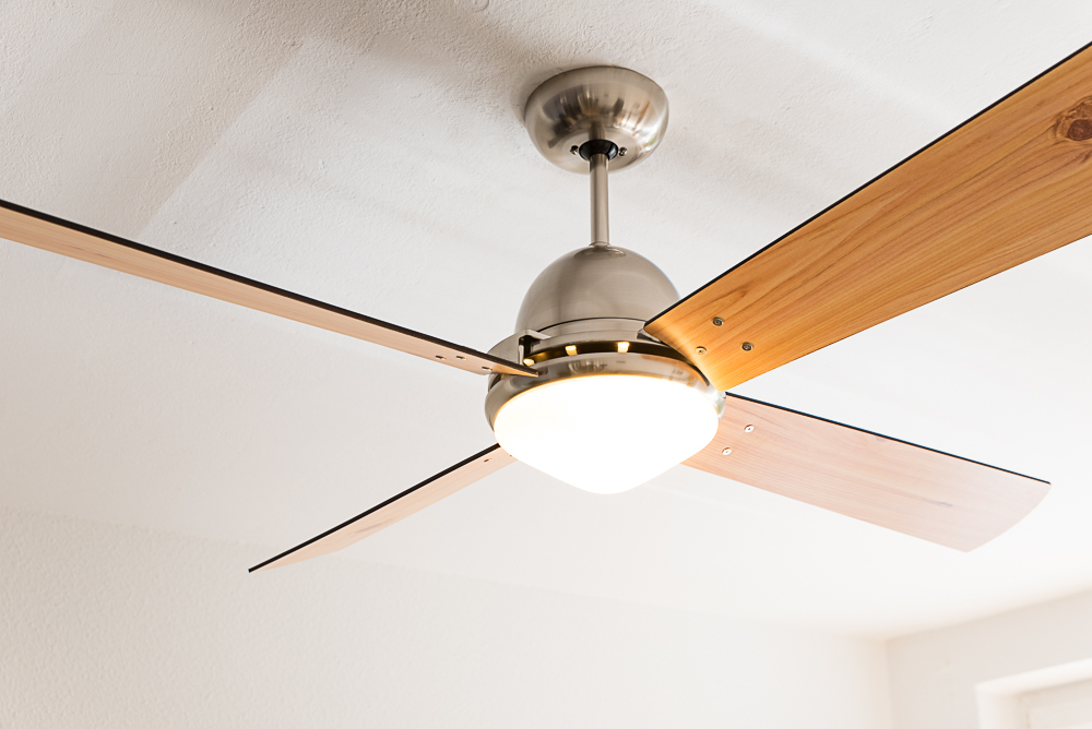 Un ventilatore da soffitto con quattro pale in legno e luce integrata.