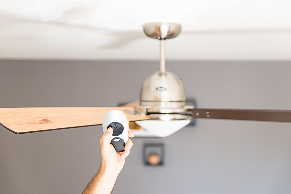 Una mano tiene un telecomando per azionare un ventilatore a soffitto.