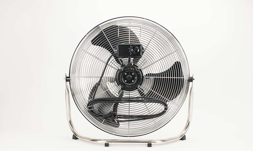 Ein schwarzer Ventilator mit Metallgitter und silbernem Gestell steht vor weißem Hintergrund.