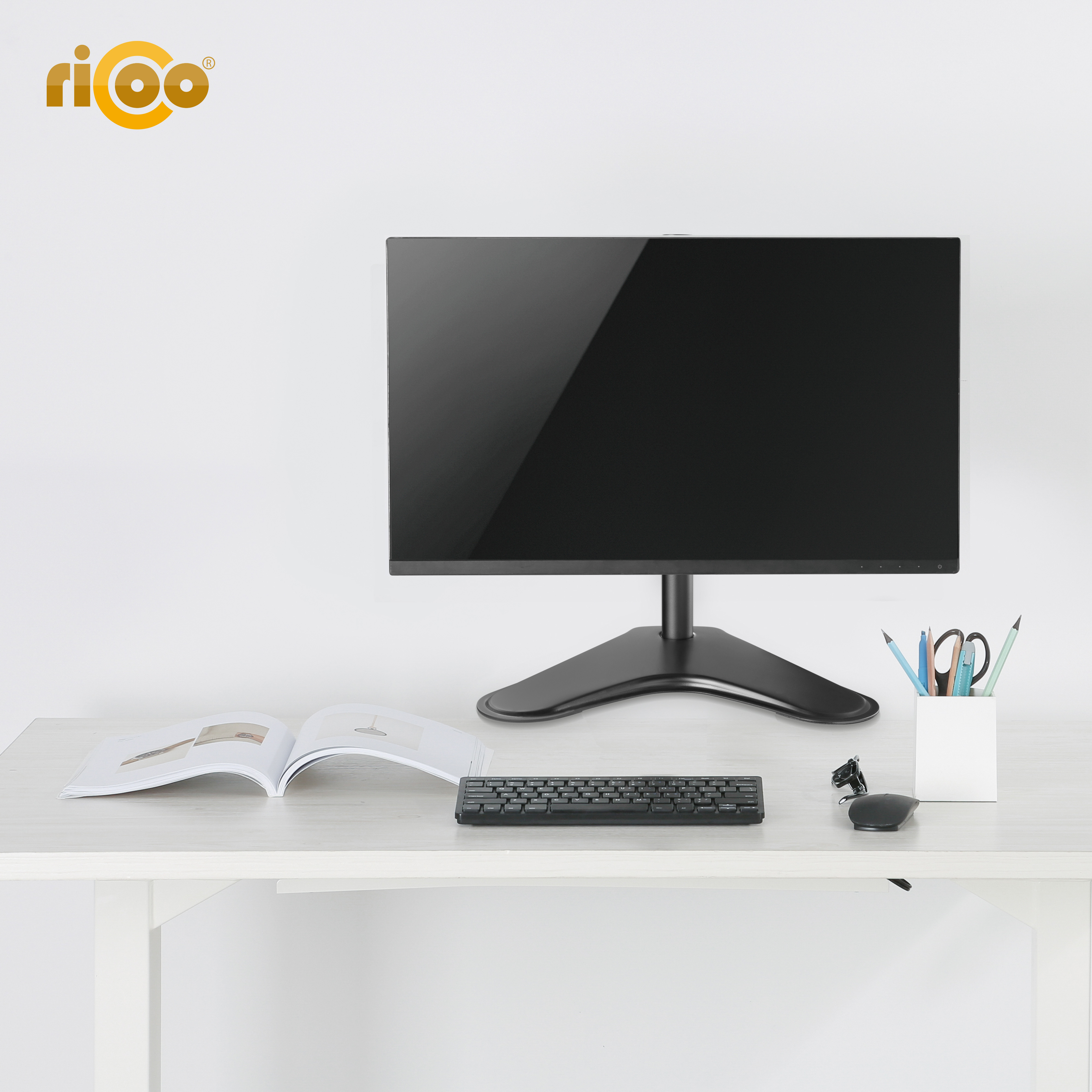 Ein Schreibtisch mit Monitor, Tastatur, Maus, offenem Buch und Stiftehalter mit Stiften.