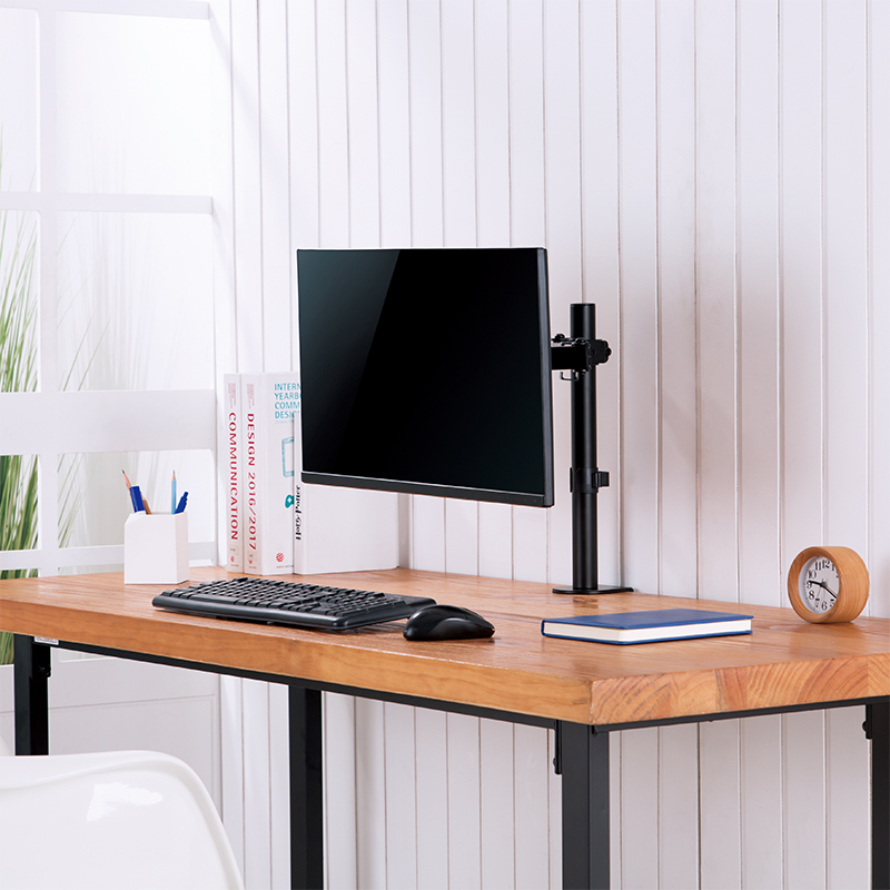 Ein Schreibtisch mit Monitor, Tastatur, Maus, Büchern und Uhr.