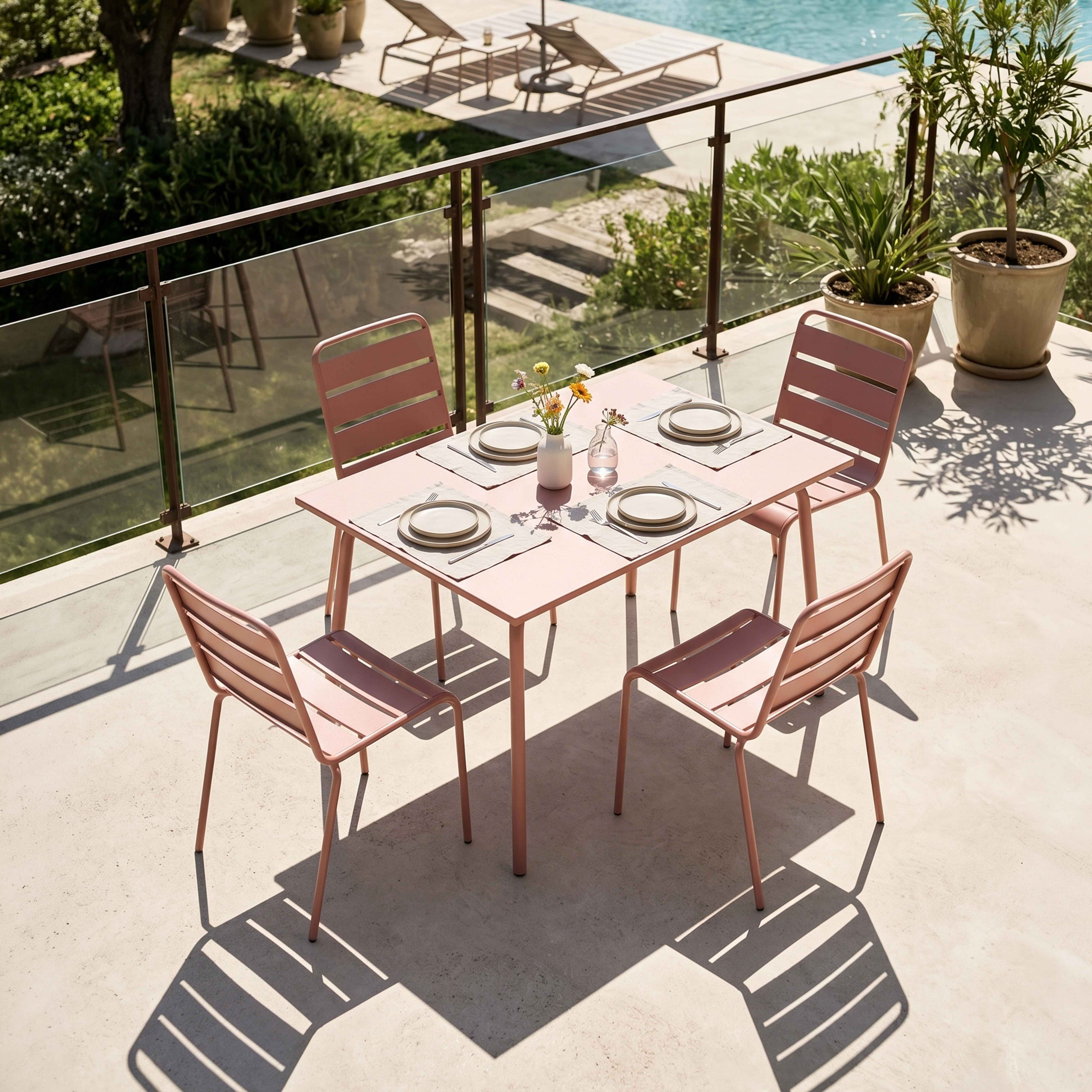 Ein rosafarbener Tisch mit vier Stühlen auf einer Terrasse mit Pool.