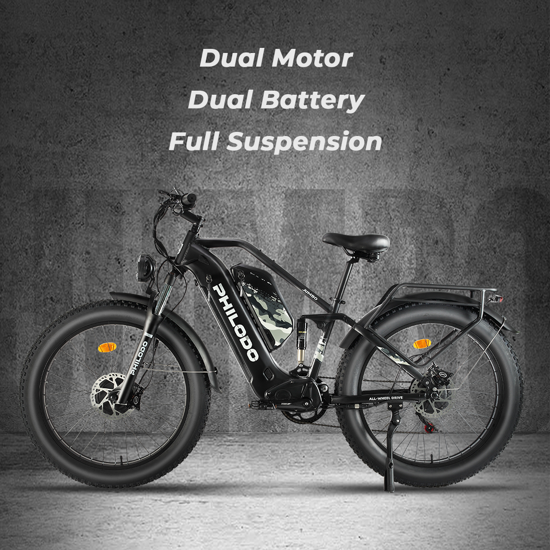 Ein schwarzes E-Bike mit fetten Reifen, Federung und Gepäckträger steht vor einer Betonwand.