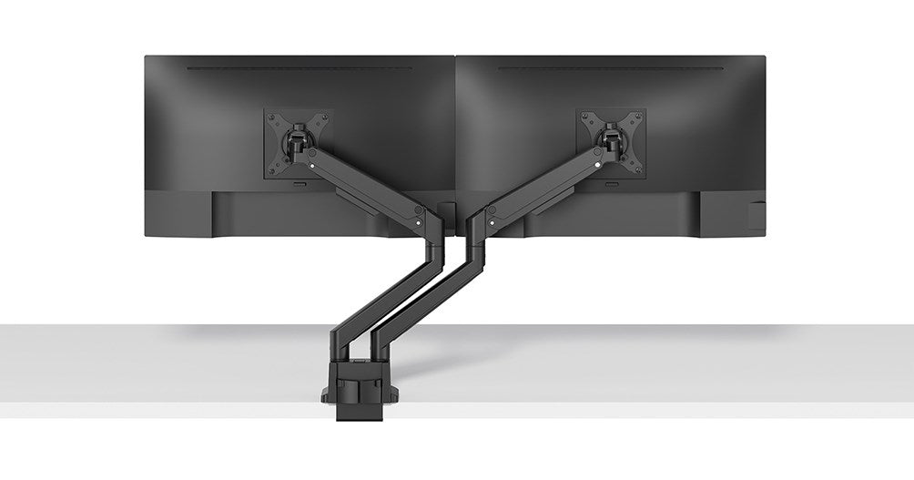 Two black monitors mounted on a dual arm stand, attached to a white desk.