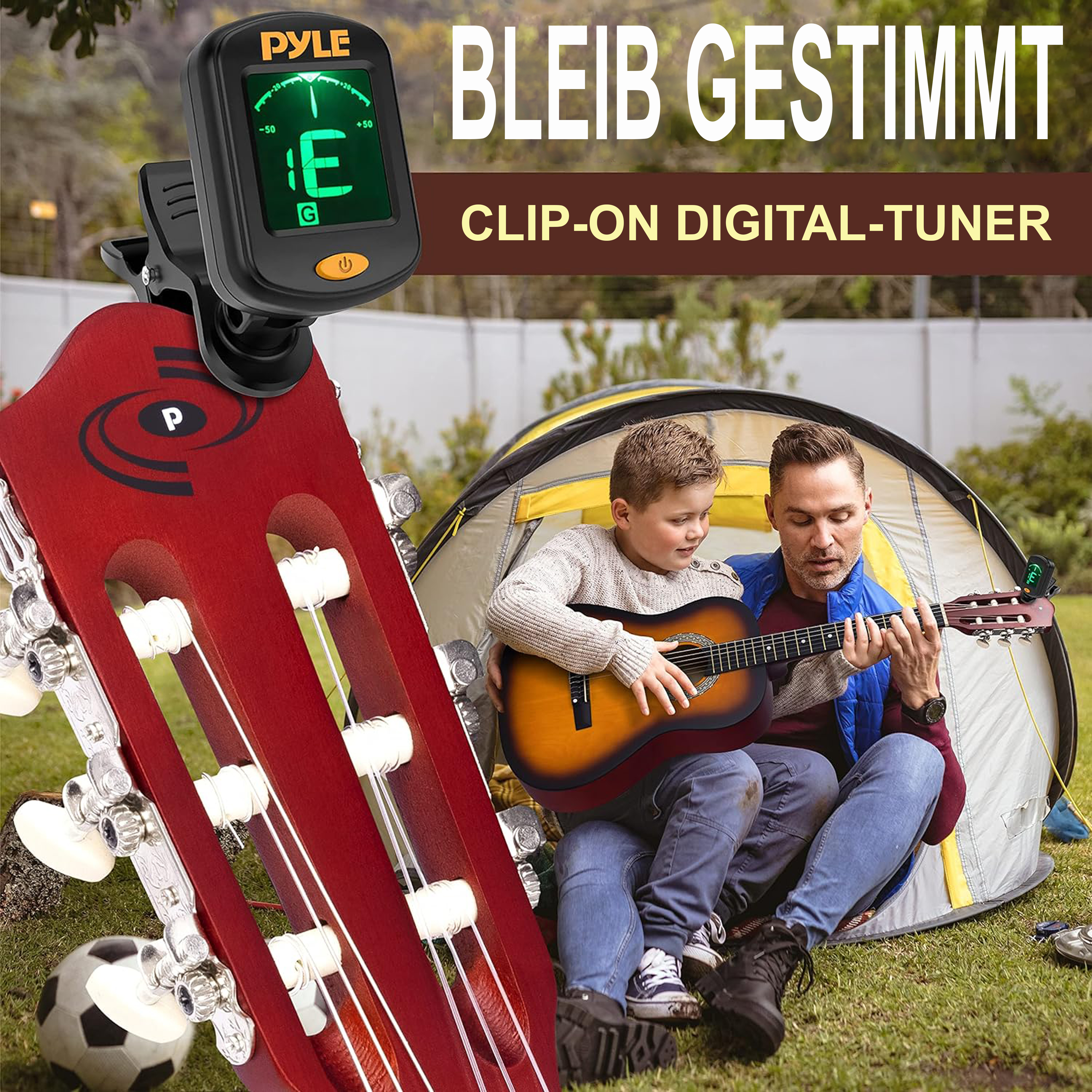 Mann und Junge stimmen Gitarre vor einem Zelt mit Stimmgerät.