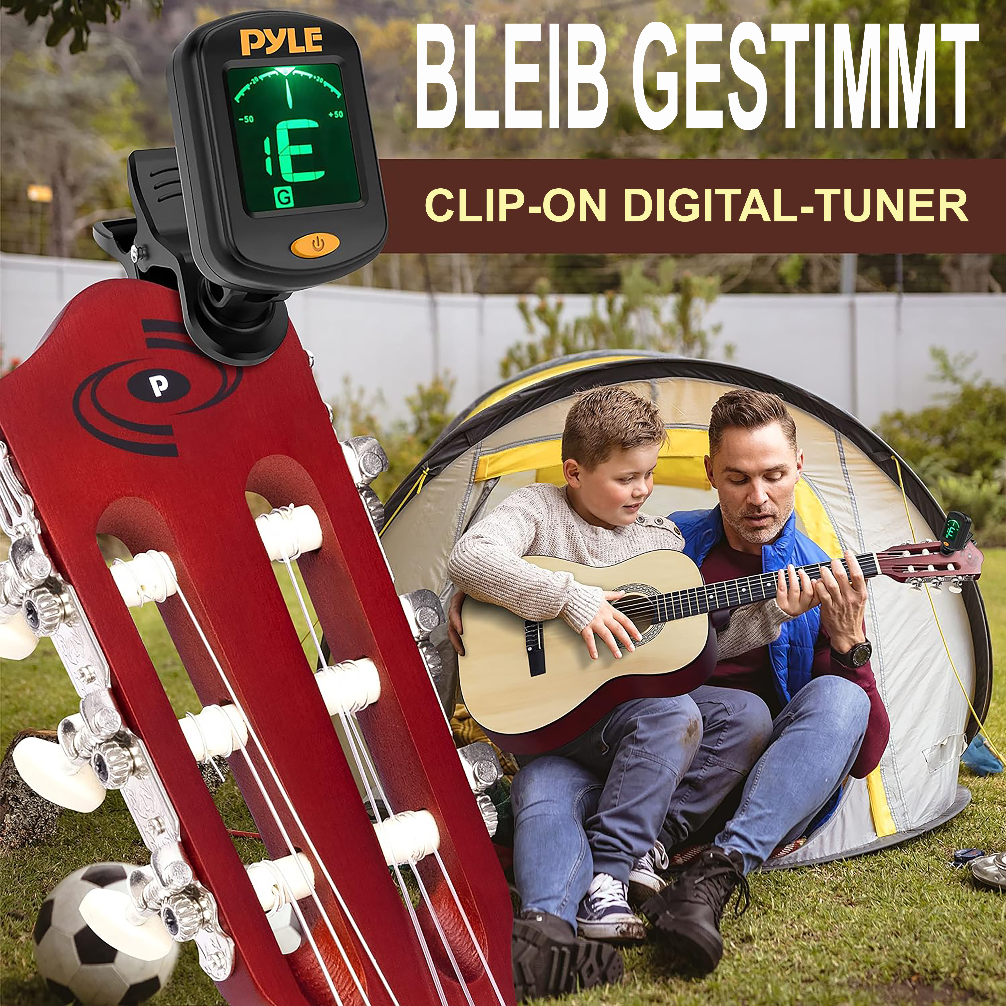 Mann und Junge stimmen Gitarre vor einem Zelt, Gitarrentuner am Kopf.