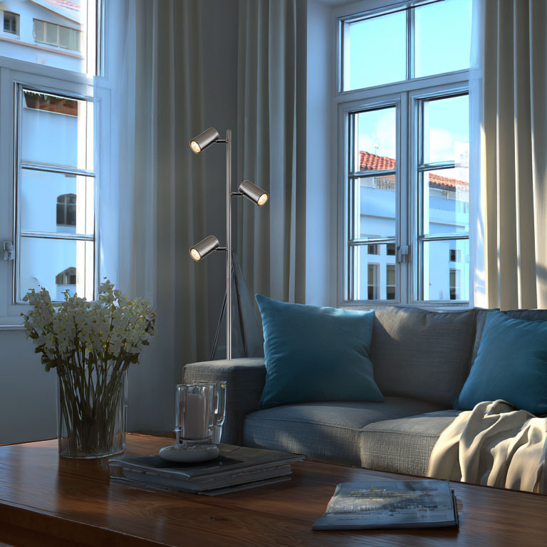 Ein moderner Stehlampe mit drei Lichtern steht neben einem Sofa.