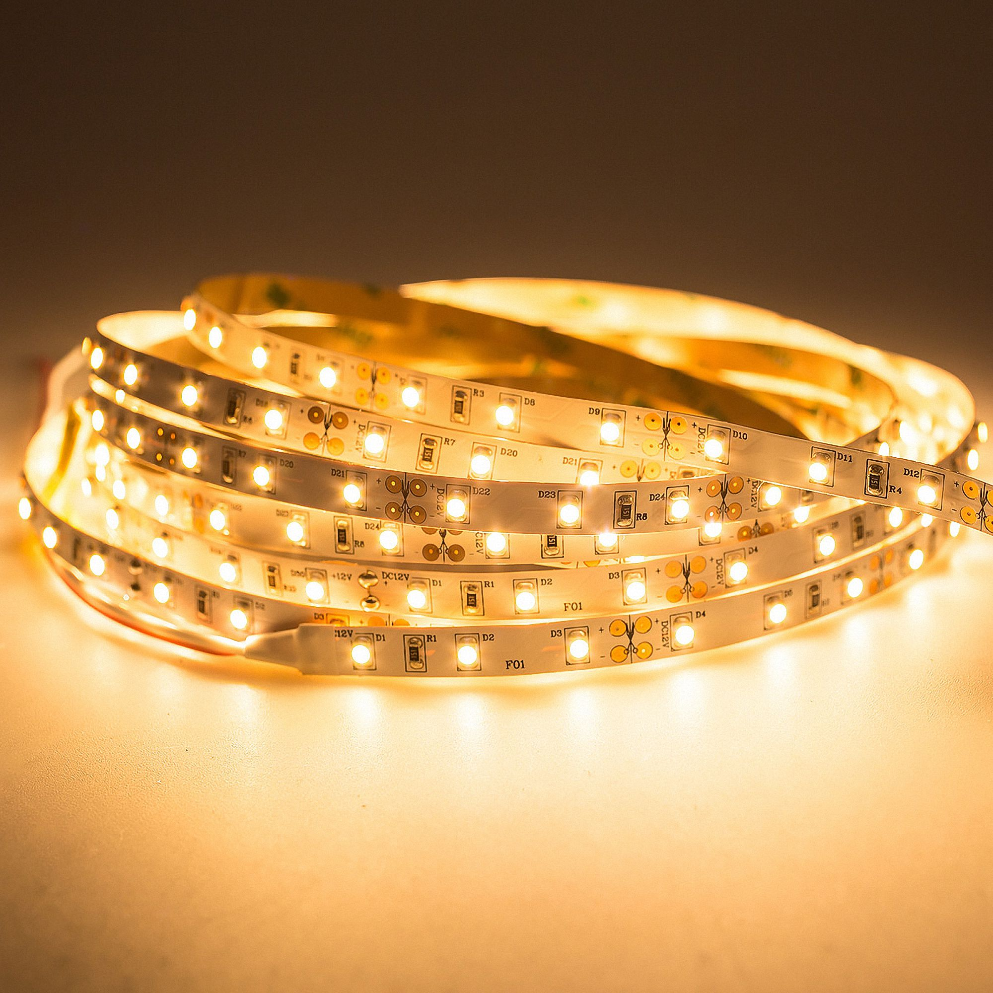 Eine aufgerollte LED-Lichtleiste mit warmweißen Lichtern auf einem hellen Untergrund.