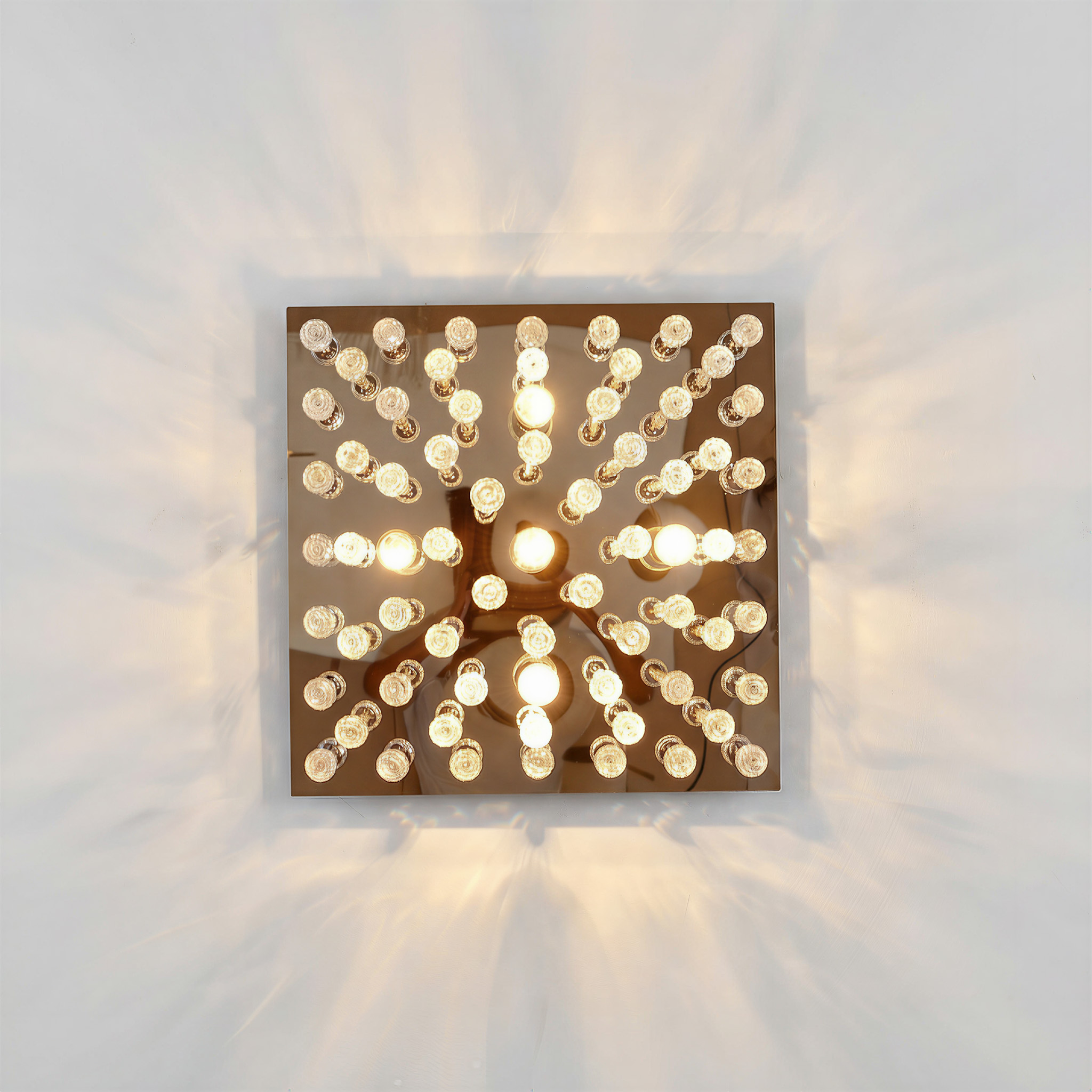 Ein quadratischer Spiegel mit vielen kleinen Glühbirnen darauf, die Licht werfen.