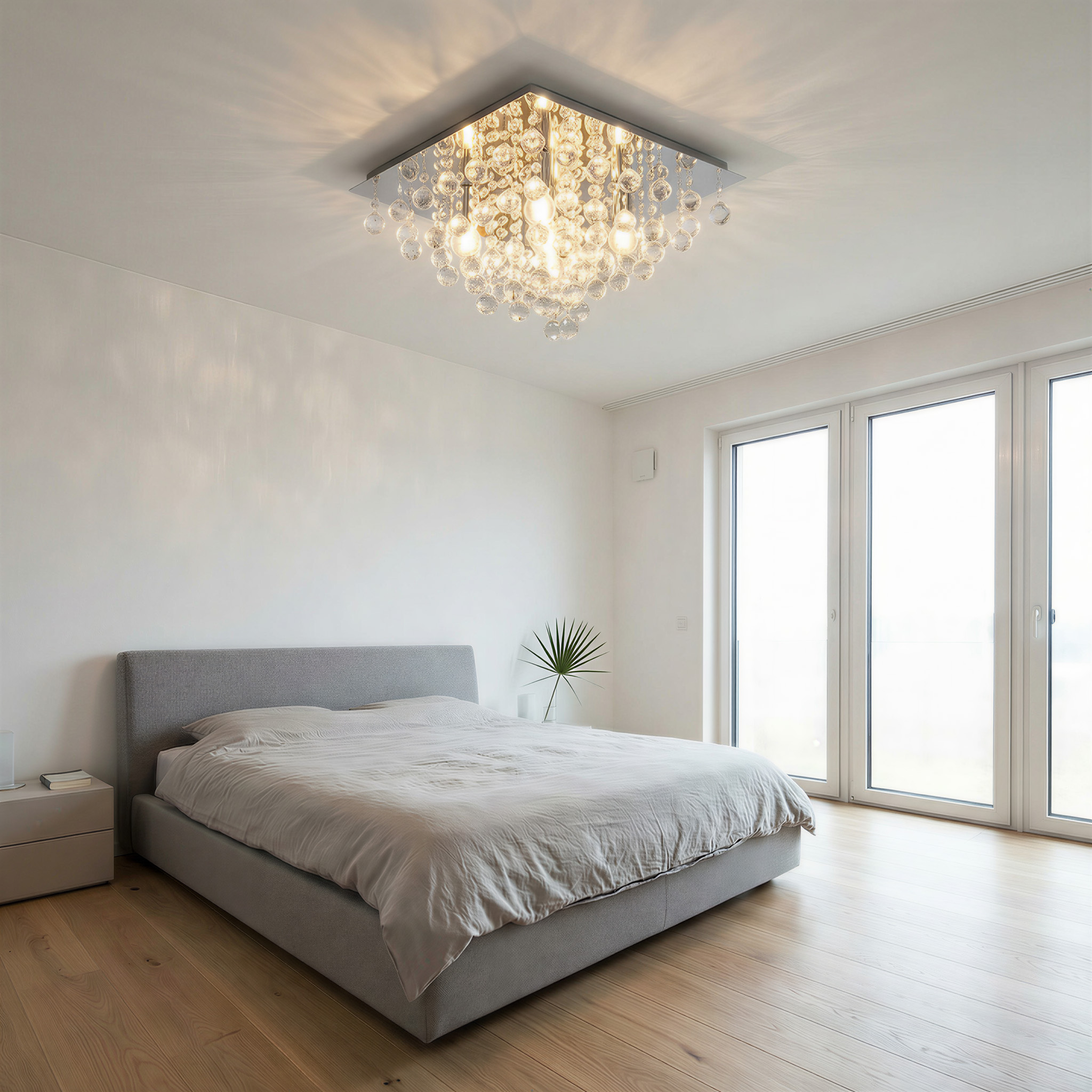 Ein modernes Schlafzimmer mit einem Bett, Nachttisch, Kristall-Deckenleuchte und groen Fenstern.