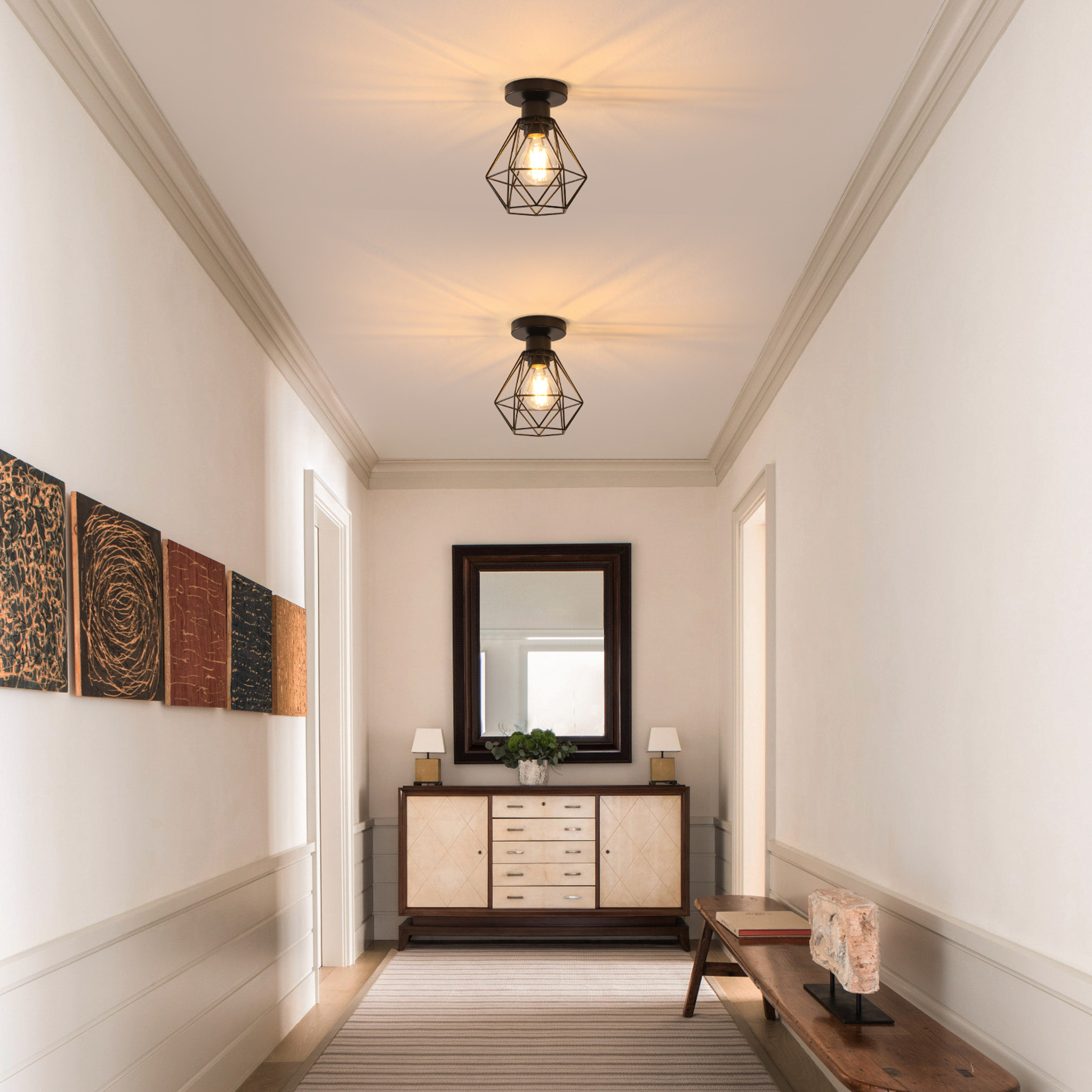 Ein langer Flur mit Kunstwerken an der Wand, einem Schrank, einem Spiegel und Lampen.