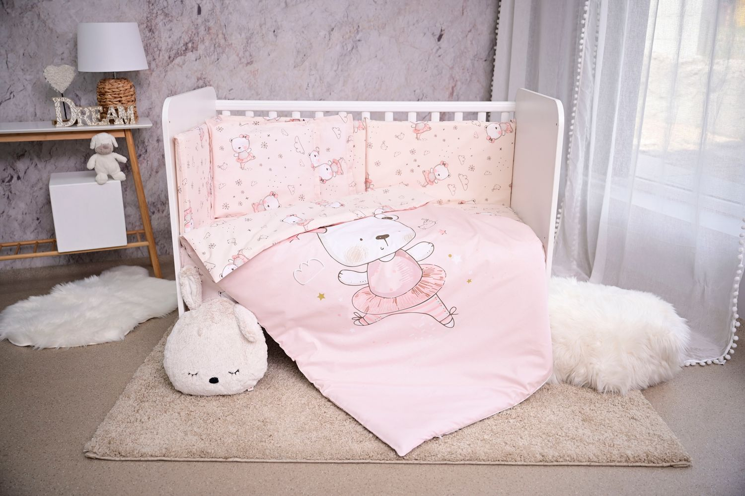 Ein rosa Bettzeug mit tanzenden Bären und Kuscheltieren in einem Kinderzimmer.