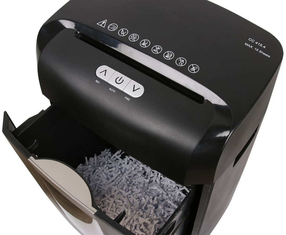 Una trituradora de papel negra con su depósito abierto, llena de papel triturado.