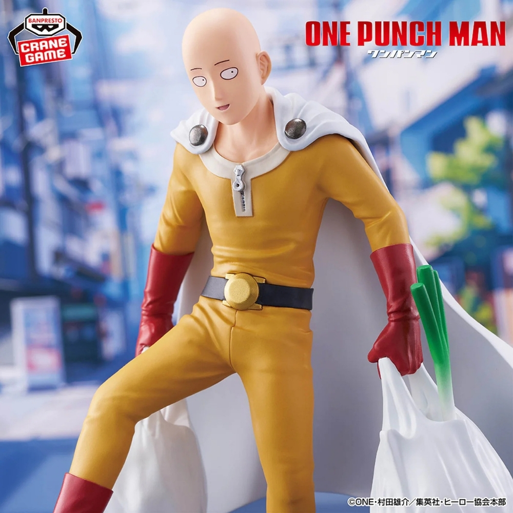 Saitama de One Punch Man con traje amarillo y capa blanca lleva una bolsa de la compra con cebolletas.