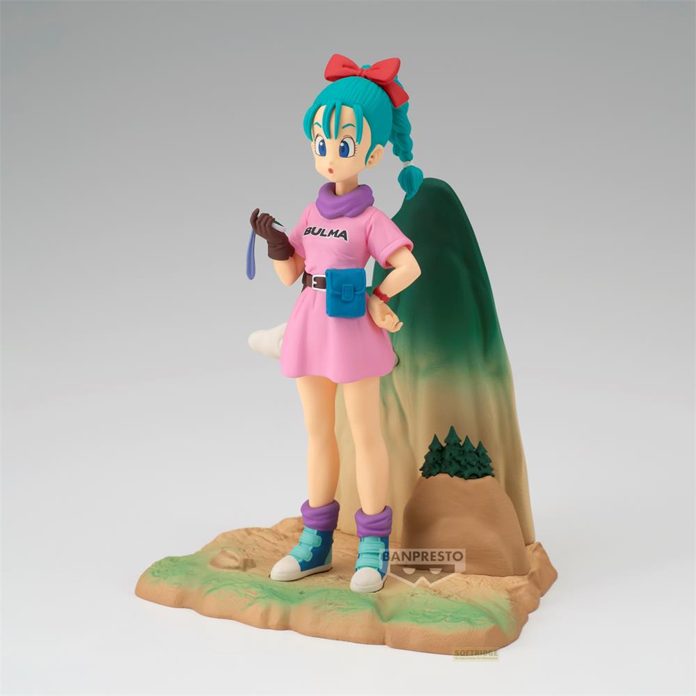 Statua di Bulma in vestito rosa con cintura blu su un paesaggio roccioso con montagna.