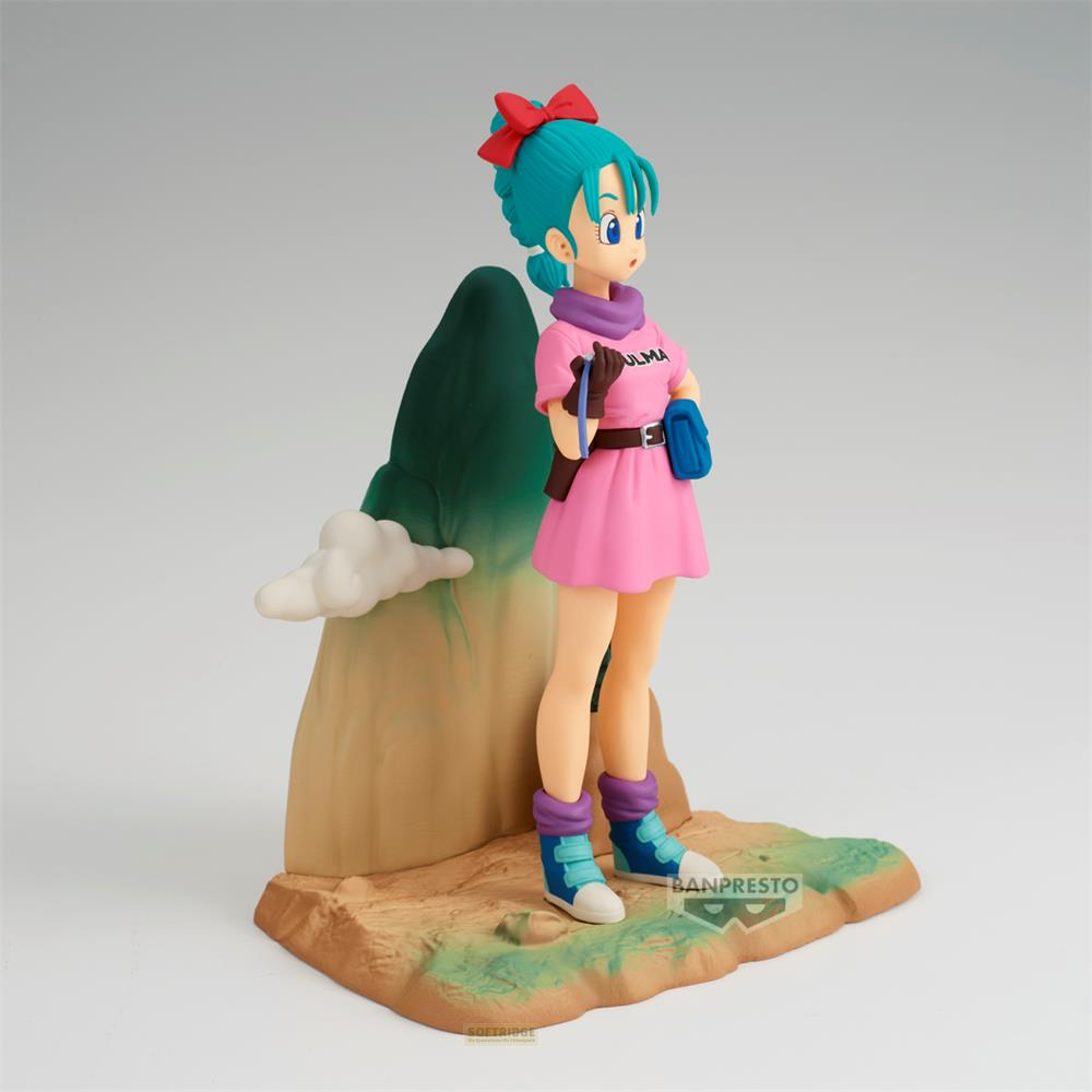 Una figura di Bulma con capelli blu e fiocco rosso, in vestito rosa, davanti a una montagna.