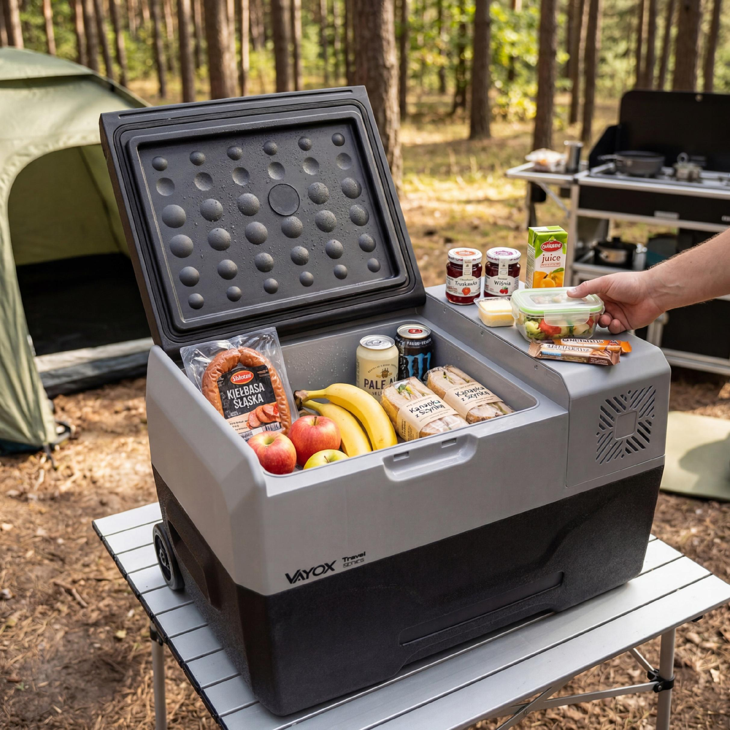 Ein offener Campingkühlschrank mit Lebensmitteln, Obst und Getränken im Wald.
