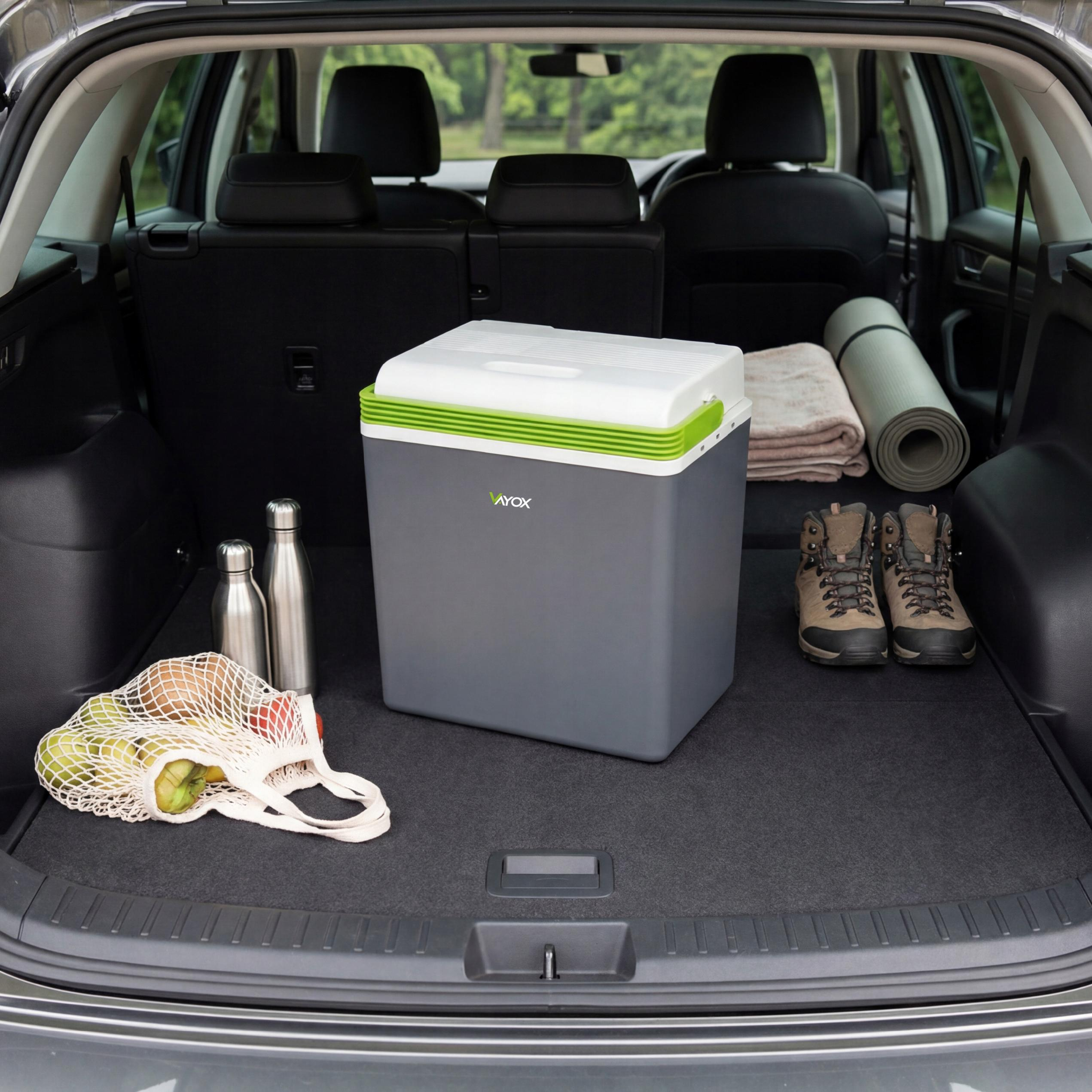 Kühler, Flaschen, Obst und Wanderschuhe im Kofferraum eines Autos.