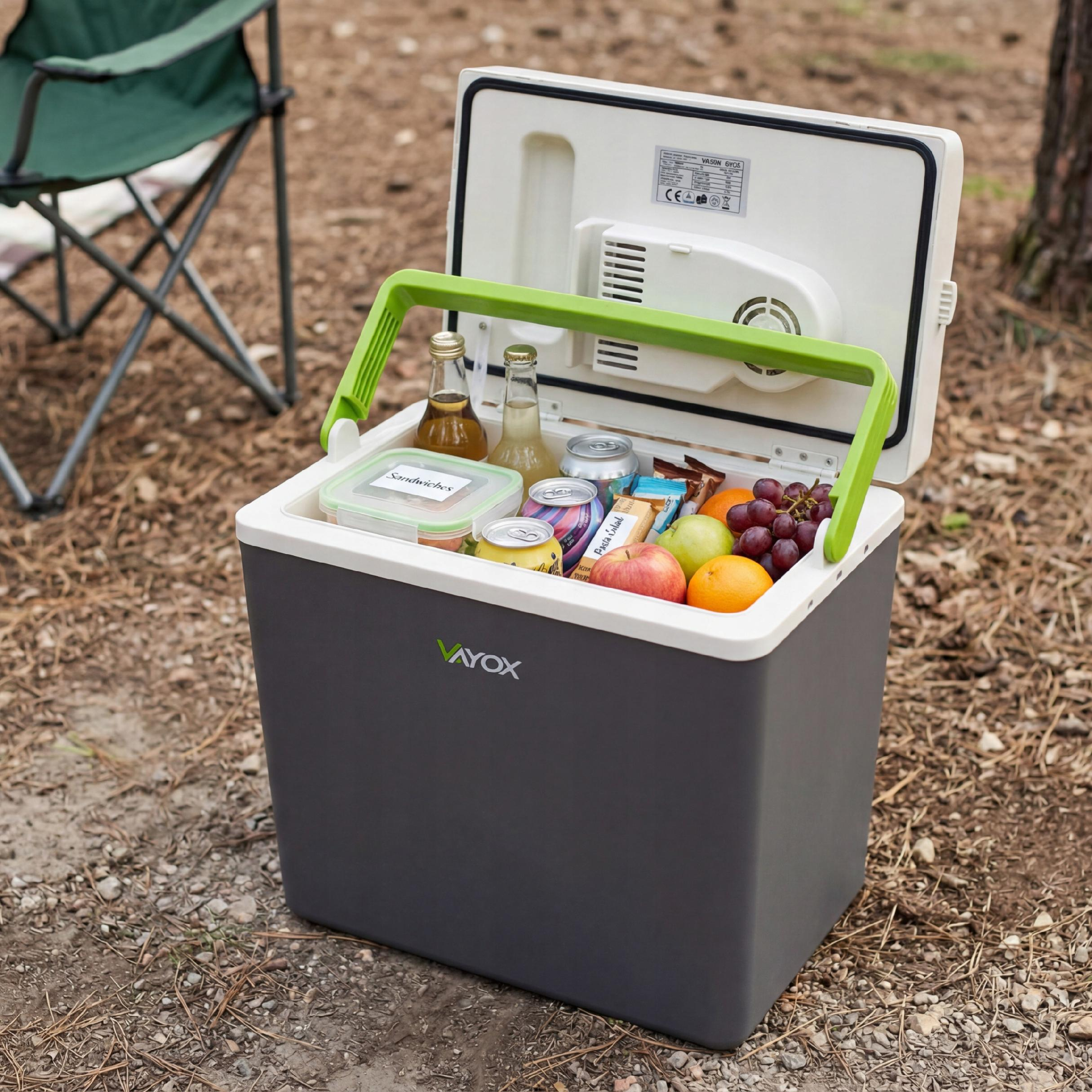 Ein offener Kühlbox mit Obst, Getränken und Snacks, draußen auf dem Boden.