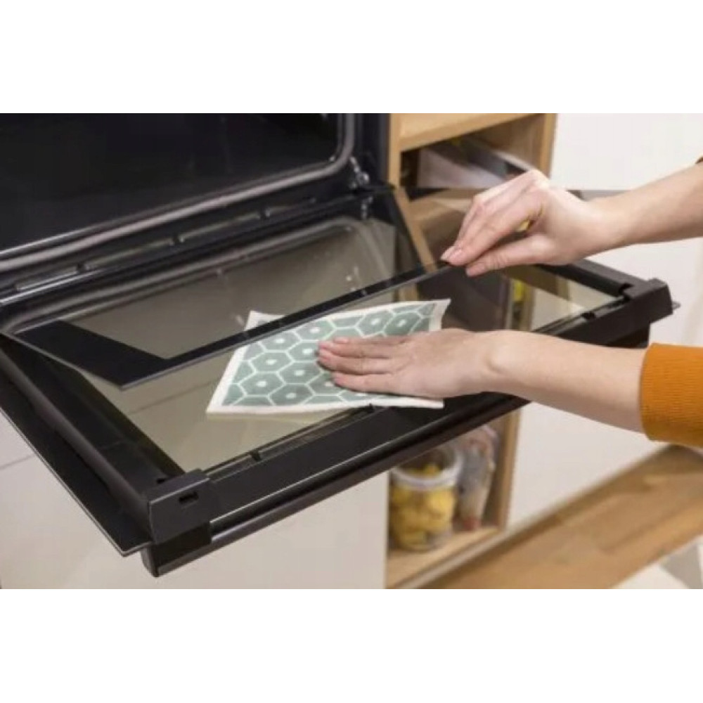 Mani puliscono il forno con un panno a motivo esagonale.
