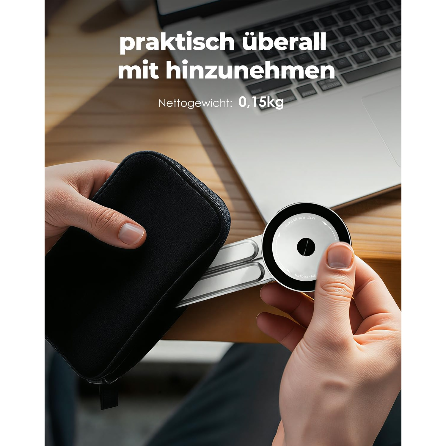 Hände halten einen schwarzen Beutel und ein silbernes Ladegerät vor einem Laptop.