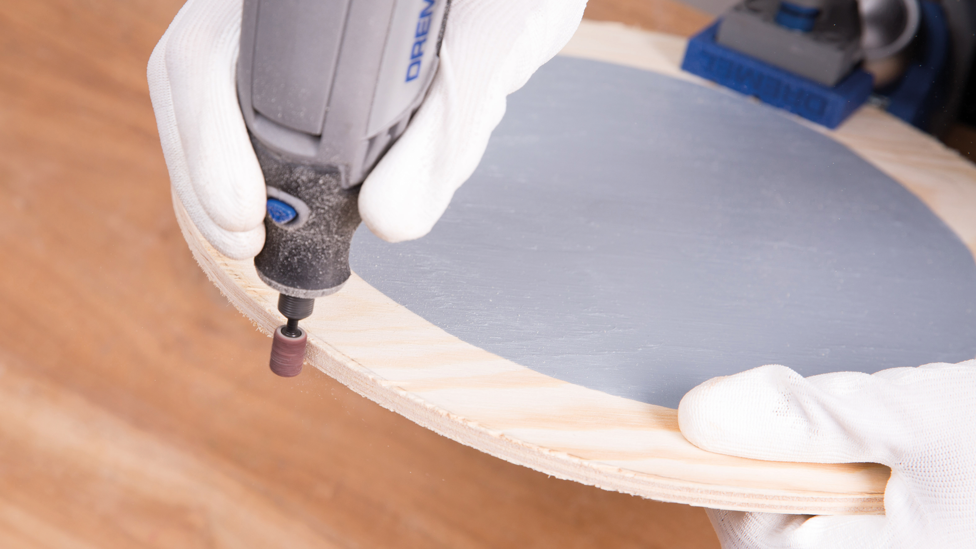 Person schleift Holzkreis mit Schleifaufsatz eines Dremel-Werkzeugs.