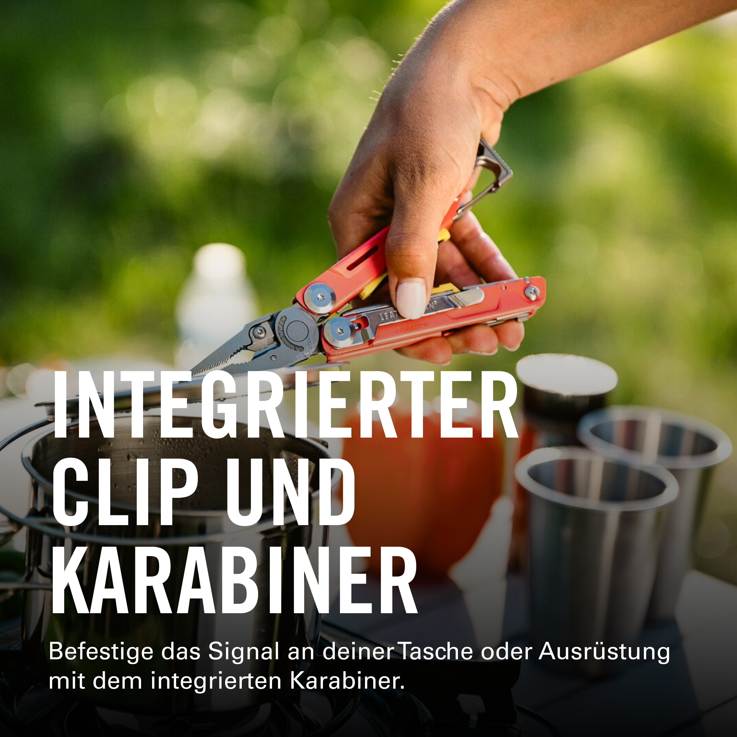 Eine Hand hält ein rotes Multitool mit integriertem Karabiner über Kochutensilien.