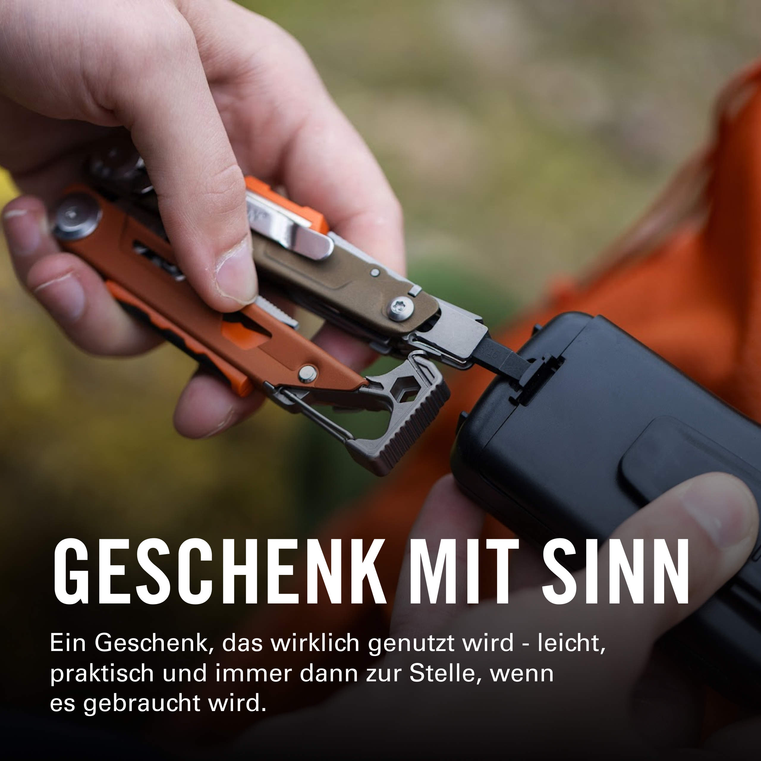 Hände halten ein Werkzeug mit orangefarbenen Griffen und einem schwarzen Kasten.