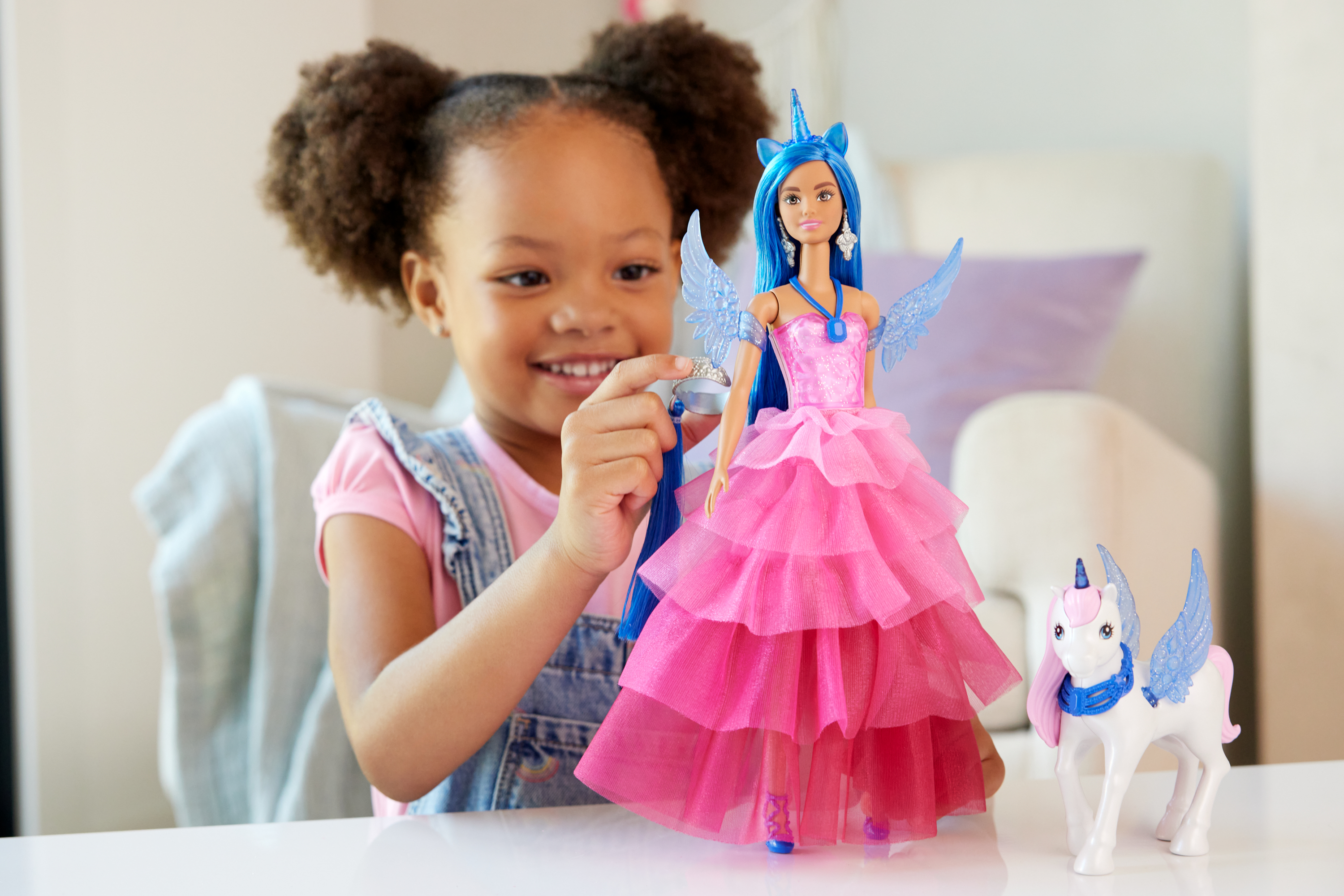 Ein kleines Mädchen spielt mit einer Barbie-Puppe und einem Einhorn.
