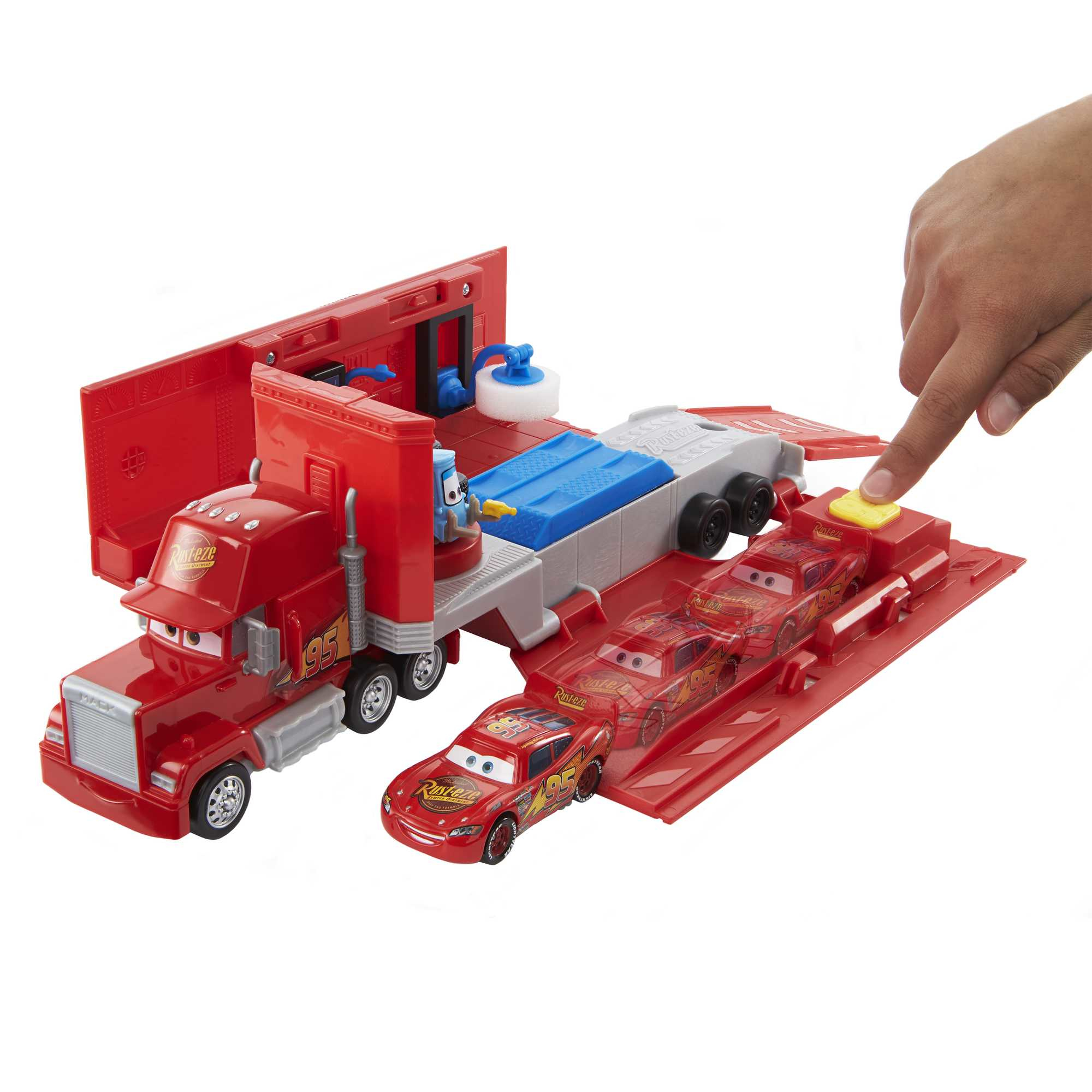 A red toy truck transporter with Lightning McQueen cars and a hand pressing a button.