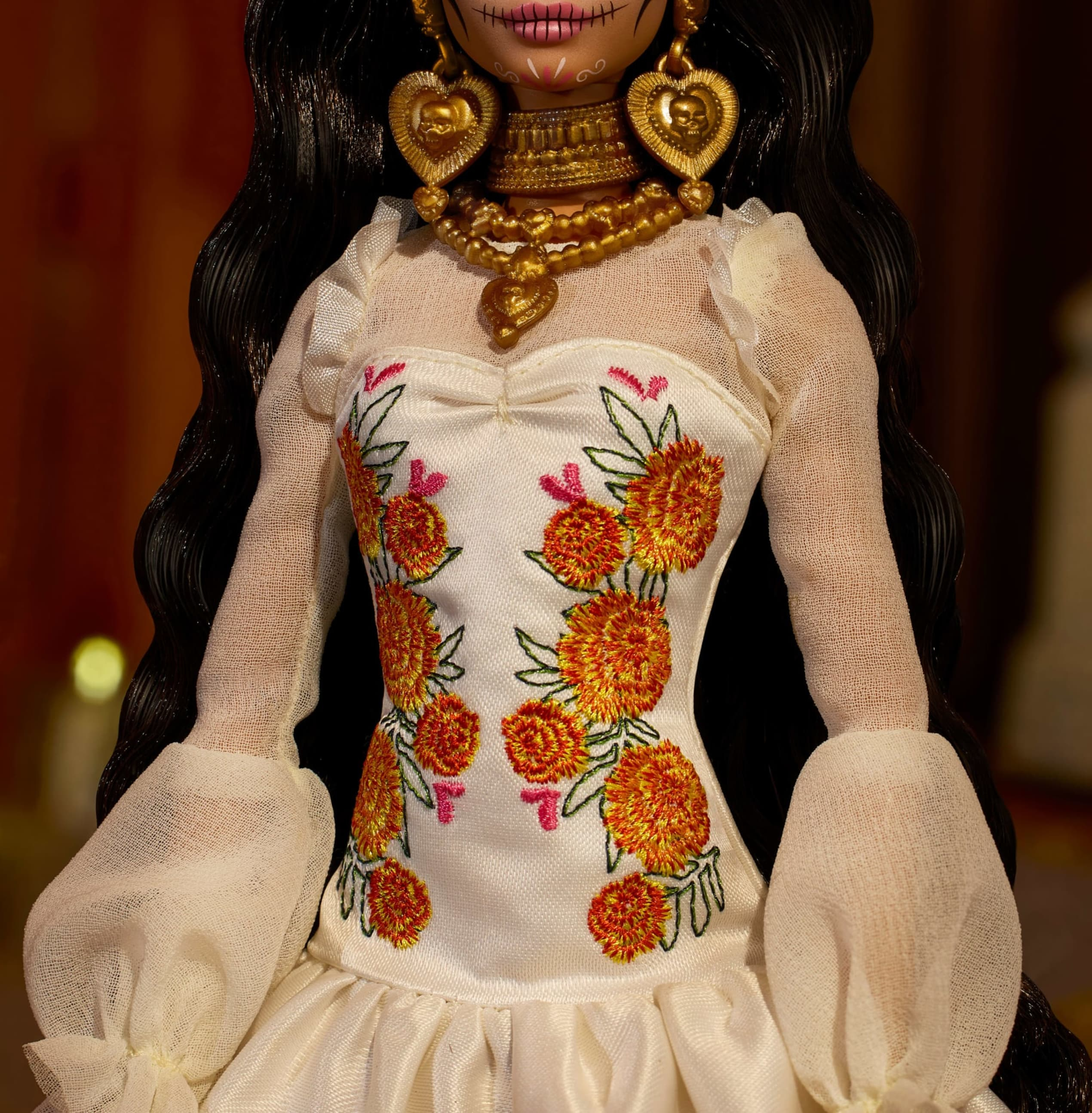 Muñeca con pelo negro, vestido blanco bordado de flores y joyas doradas.