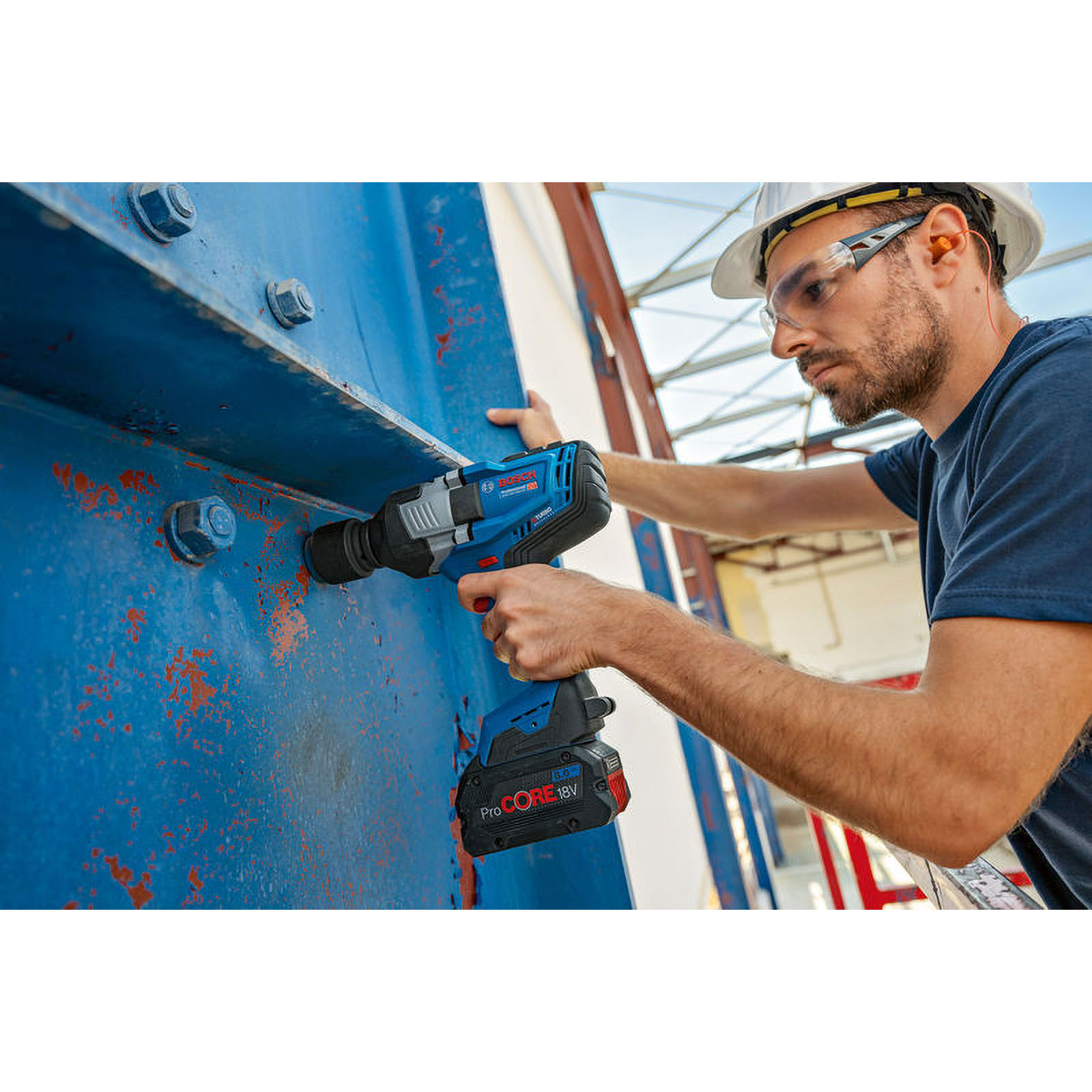 Mann mit Bohrer an blauer Metallstruktur