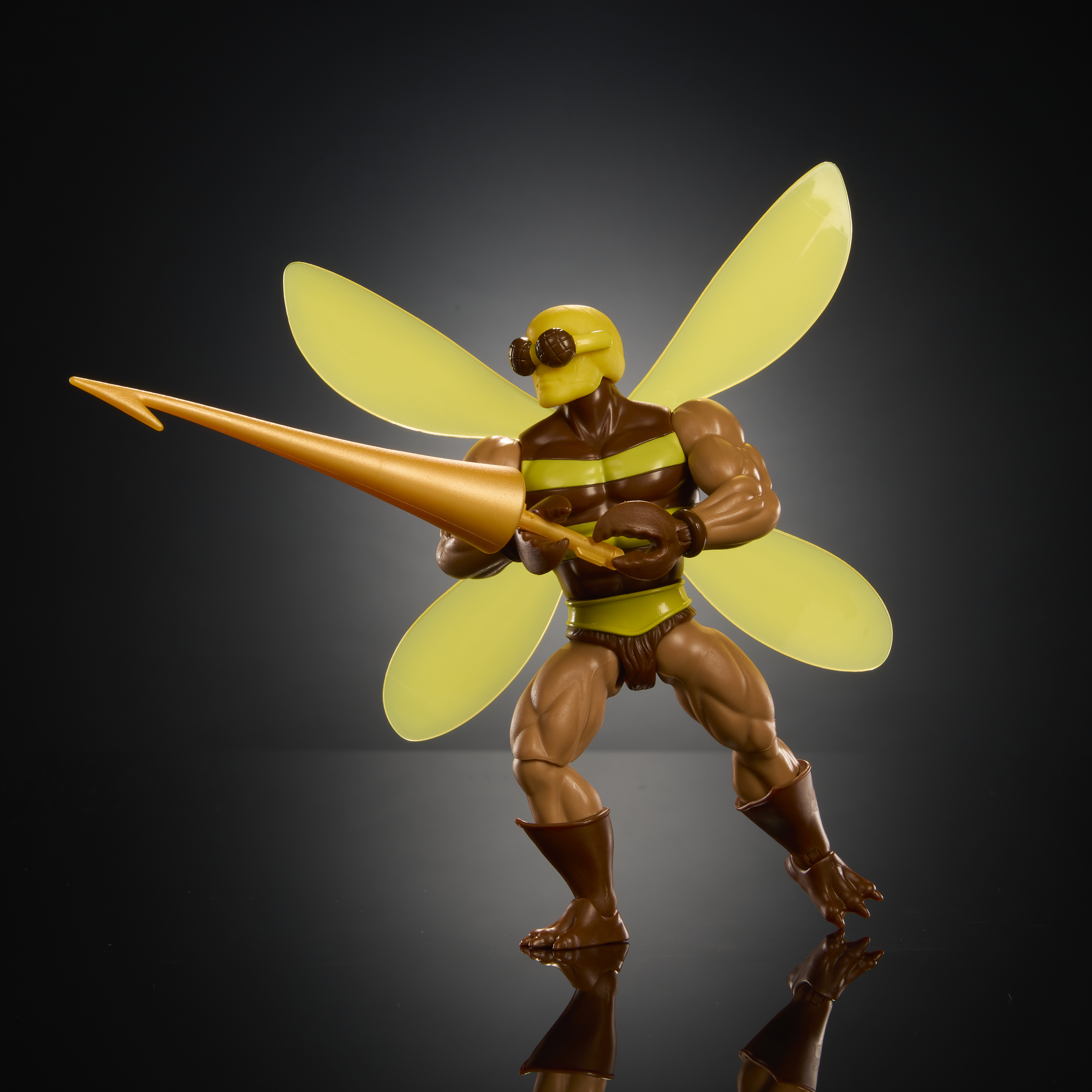 Figura de juguete con cabeza amarilla, rayas marrones y alas, sostiene una lanza dorada.