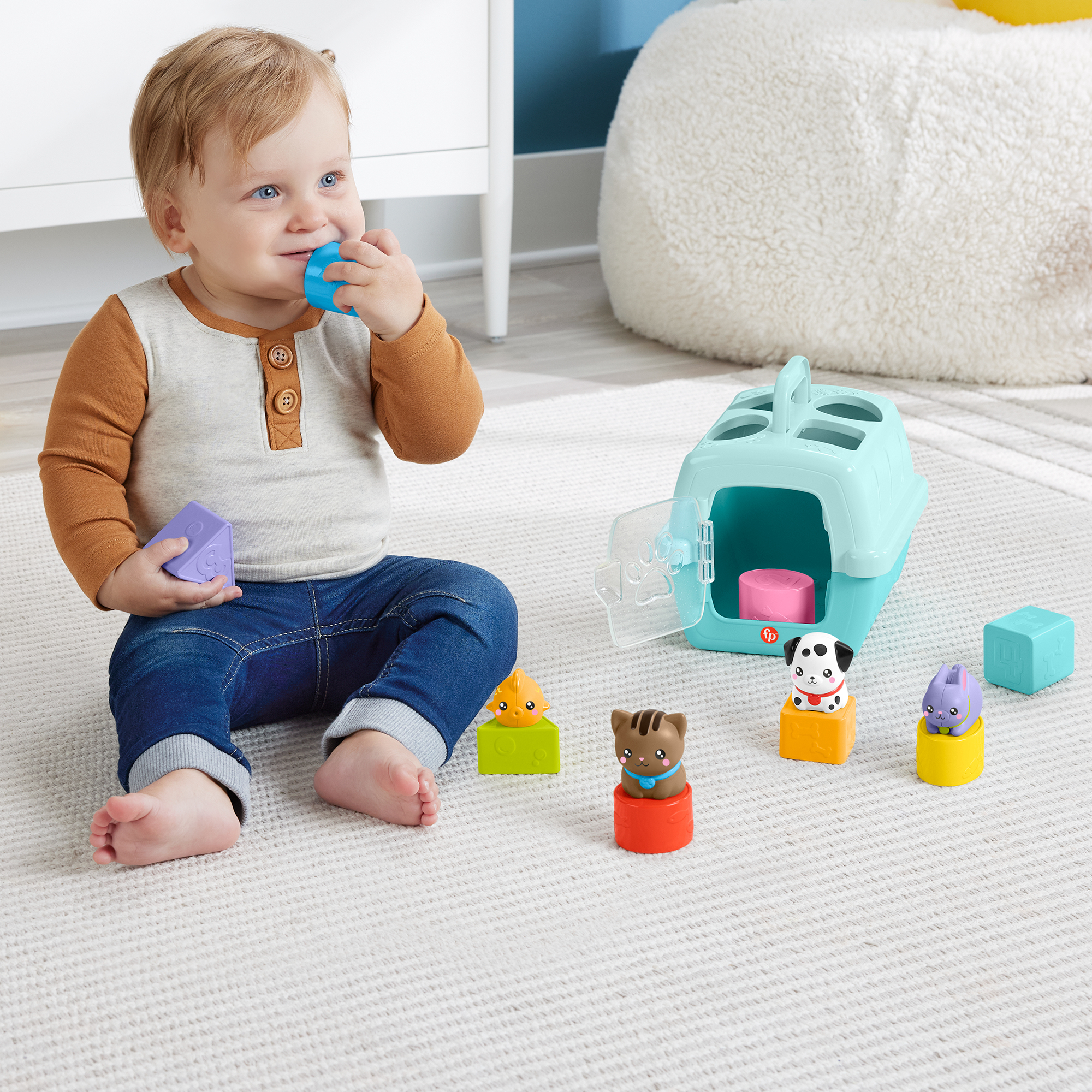 Ein Baby spielt mit bunten Tierfiguren und einem Tierkäfig-Spielzeug auf einem Teppich.
