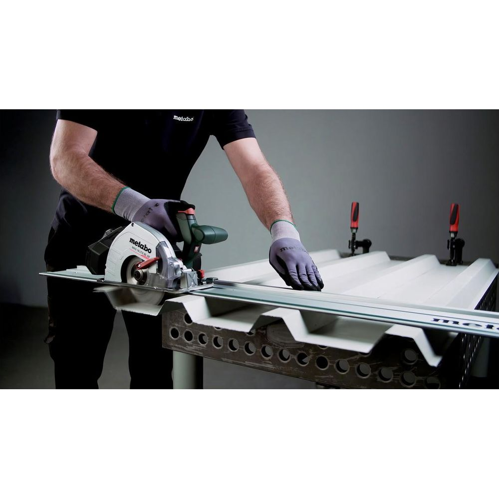 Mann mit Handschuhen schneidet mit Kreissäge auf Metallprofil.