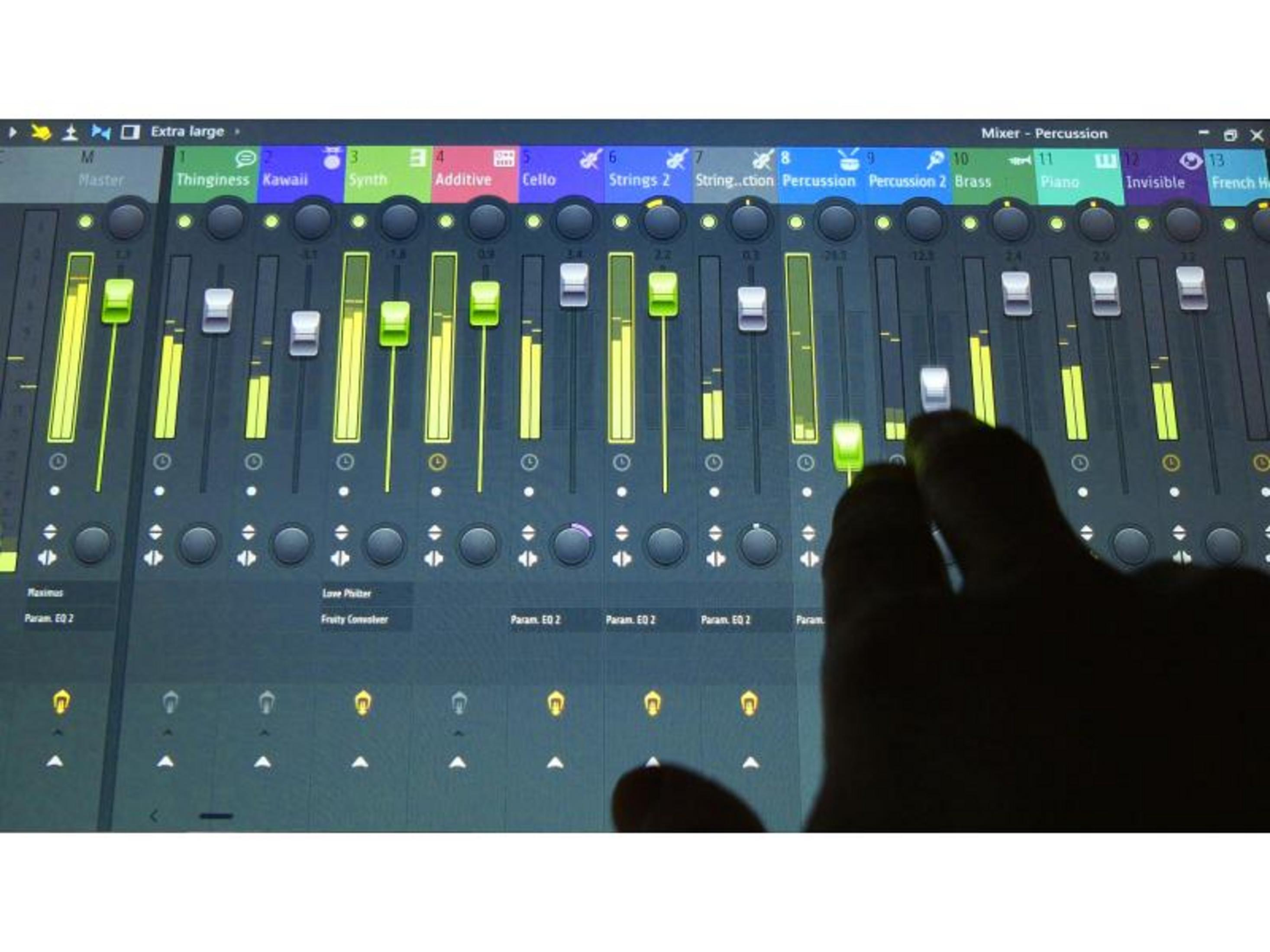 A hand operates a digital mixer with colored level meters.