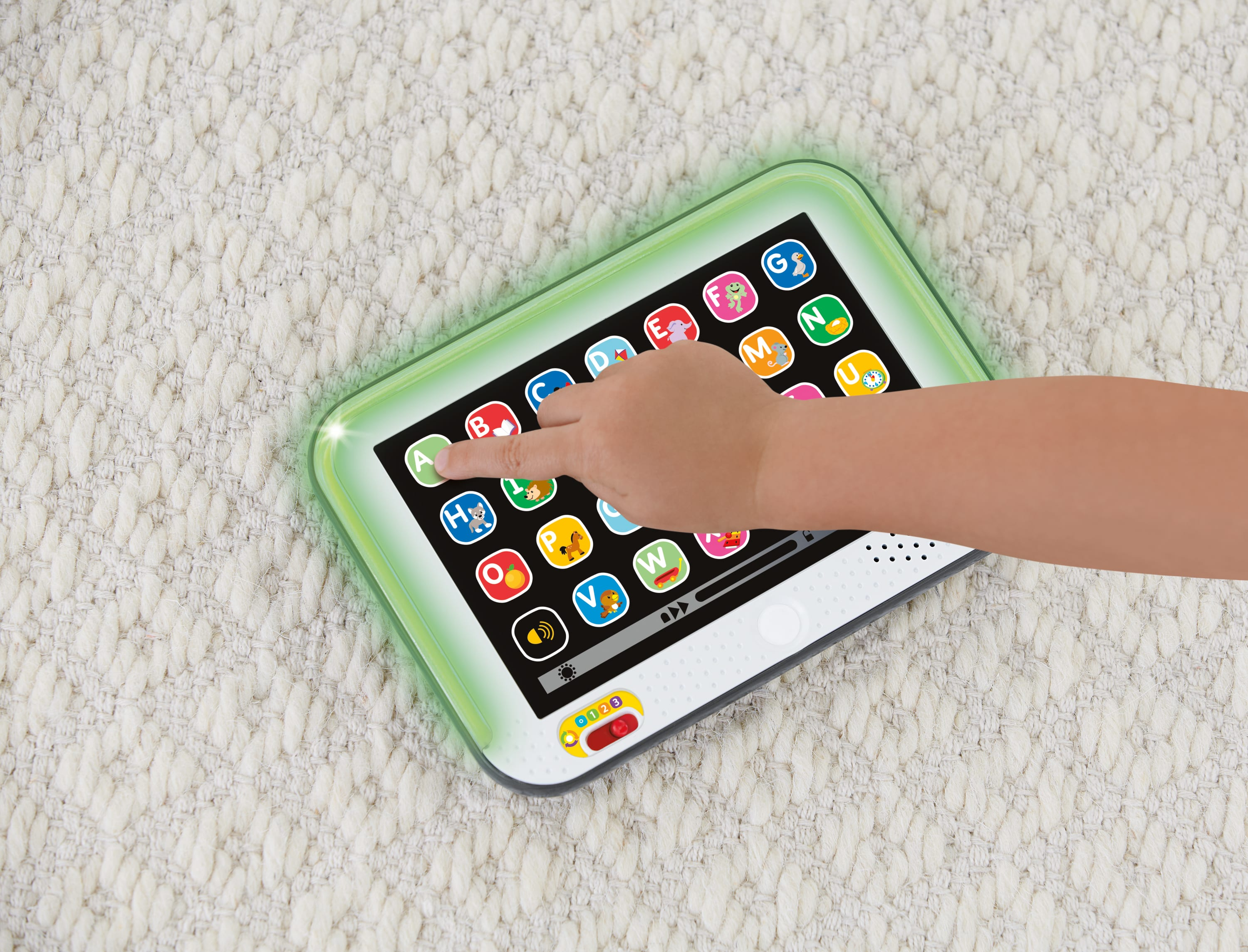 Un doigt d'enfant appuie sur la lettre A d'une tablette jouet.