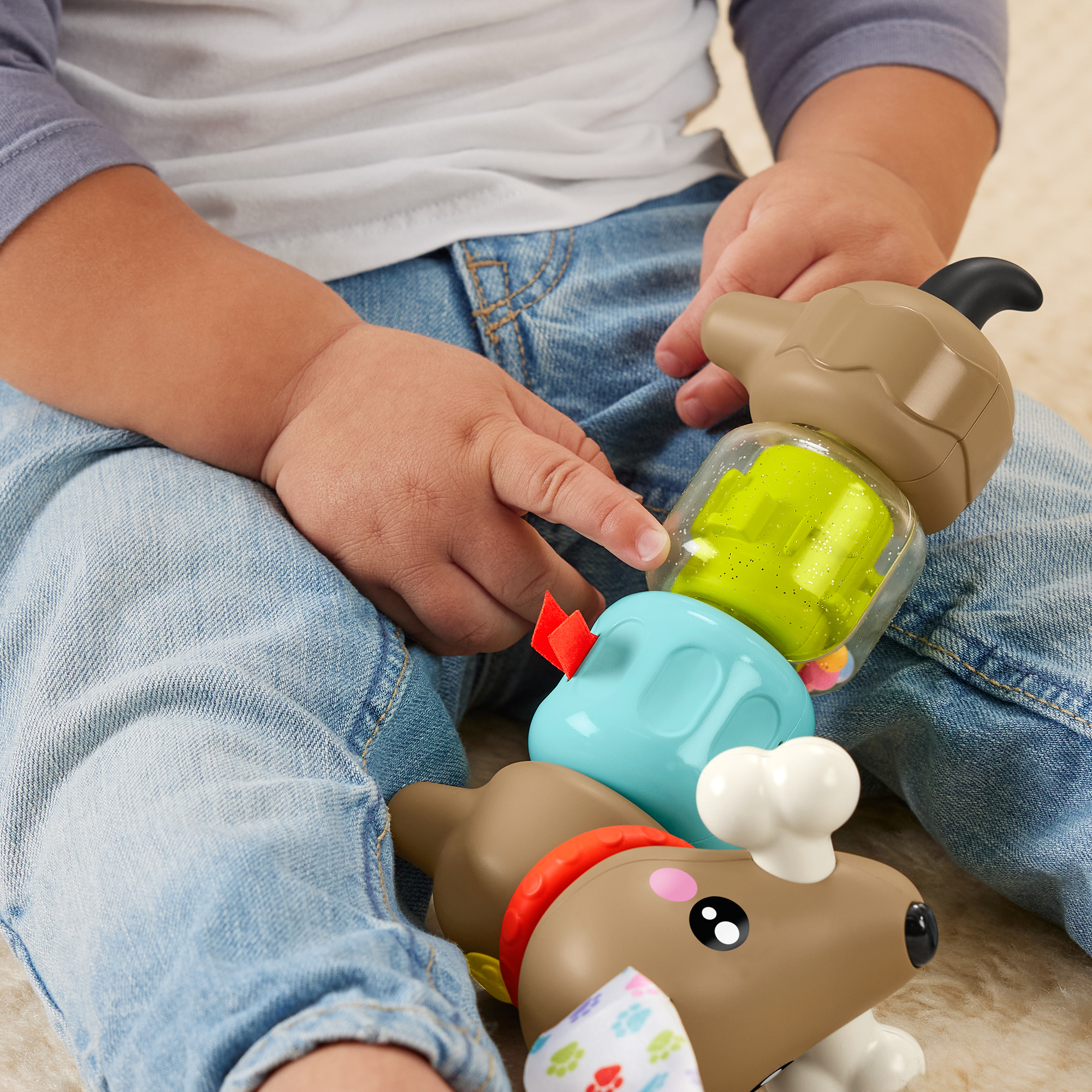 Ein Baby spielt mit einem bunten Stapelspielzeug in Hundeform.