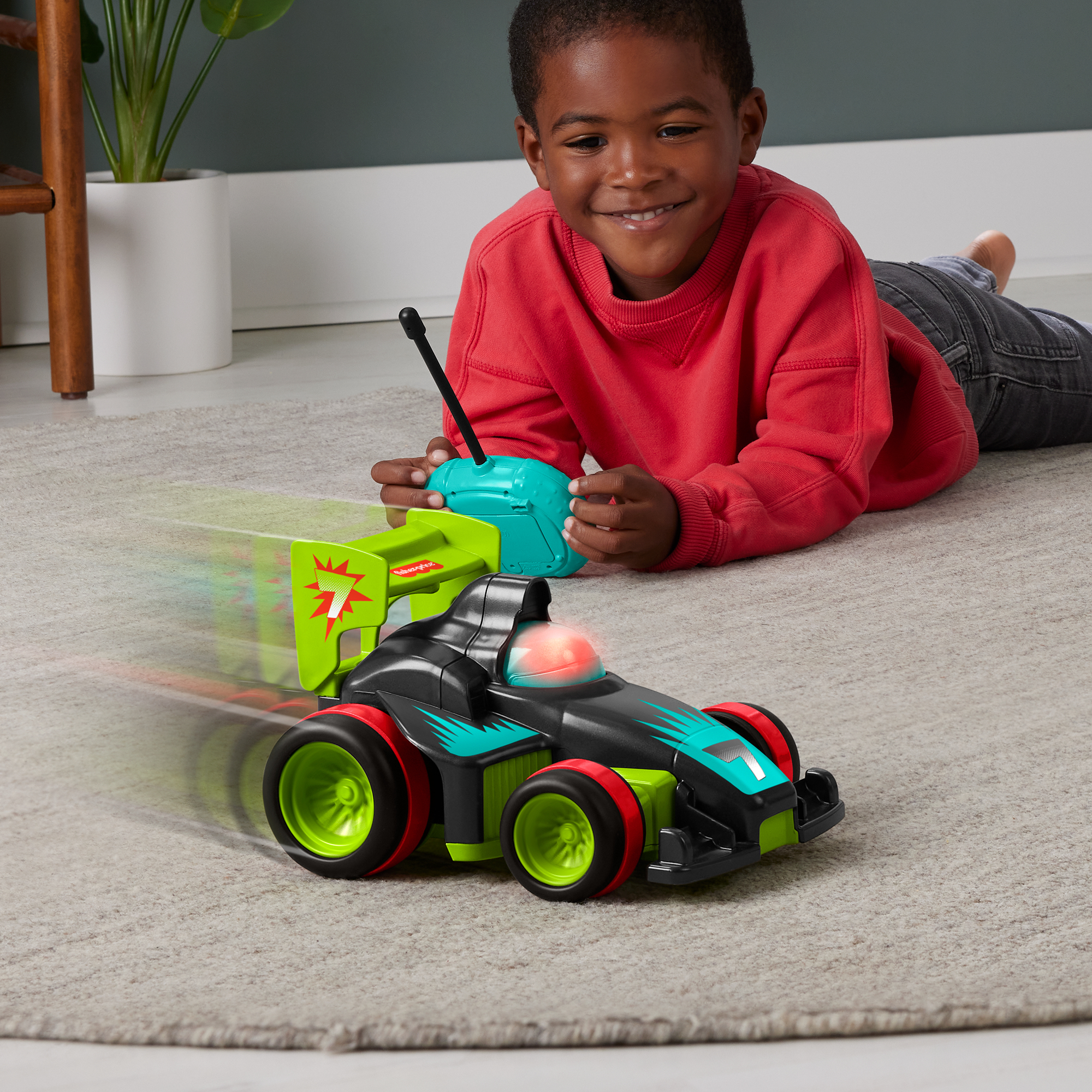 Un niño está tumbado jugando con un coche a control remoto.